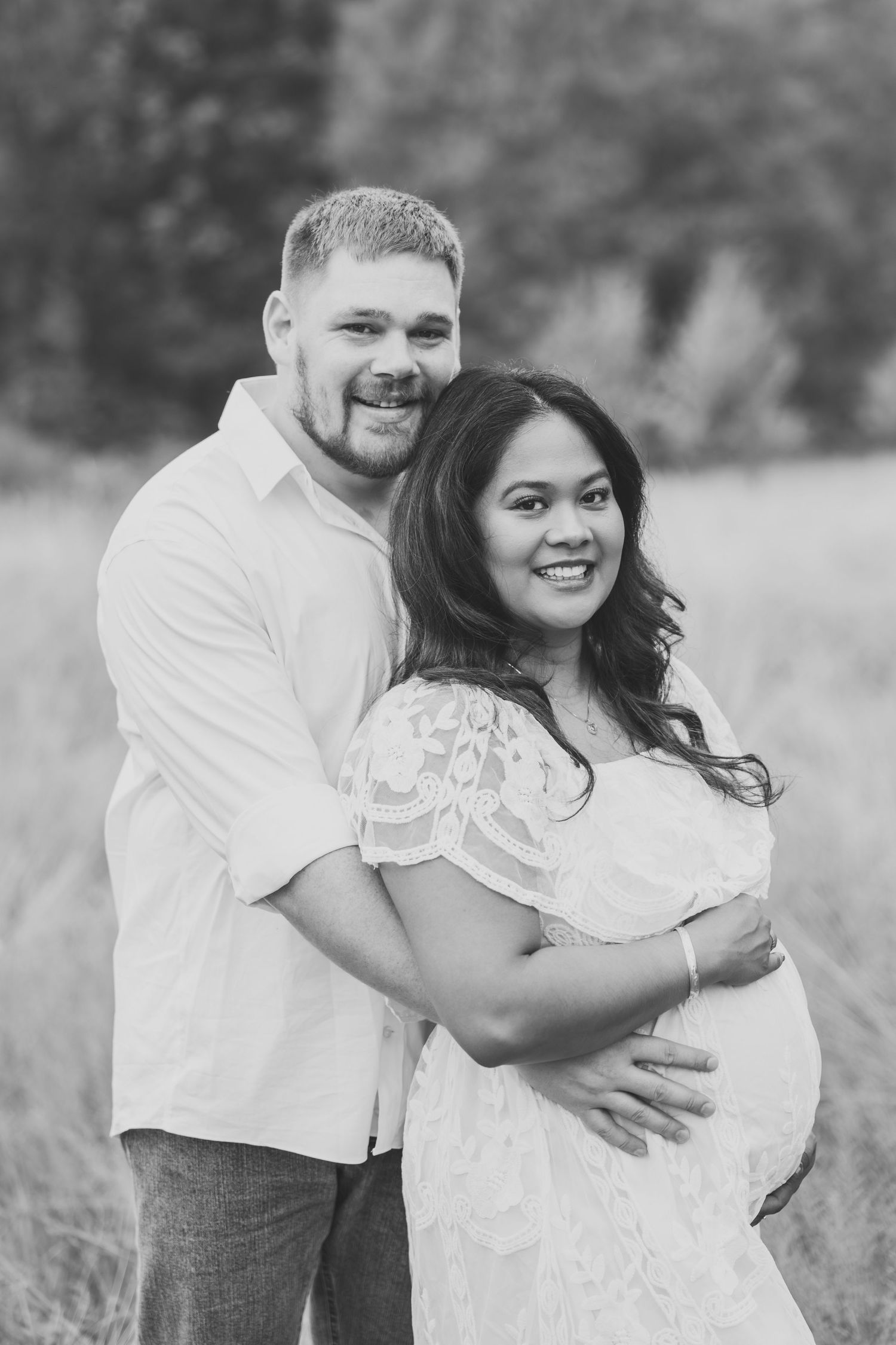 Couple embracing and laughing together in black and white outdoor portrait.