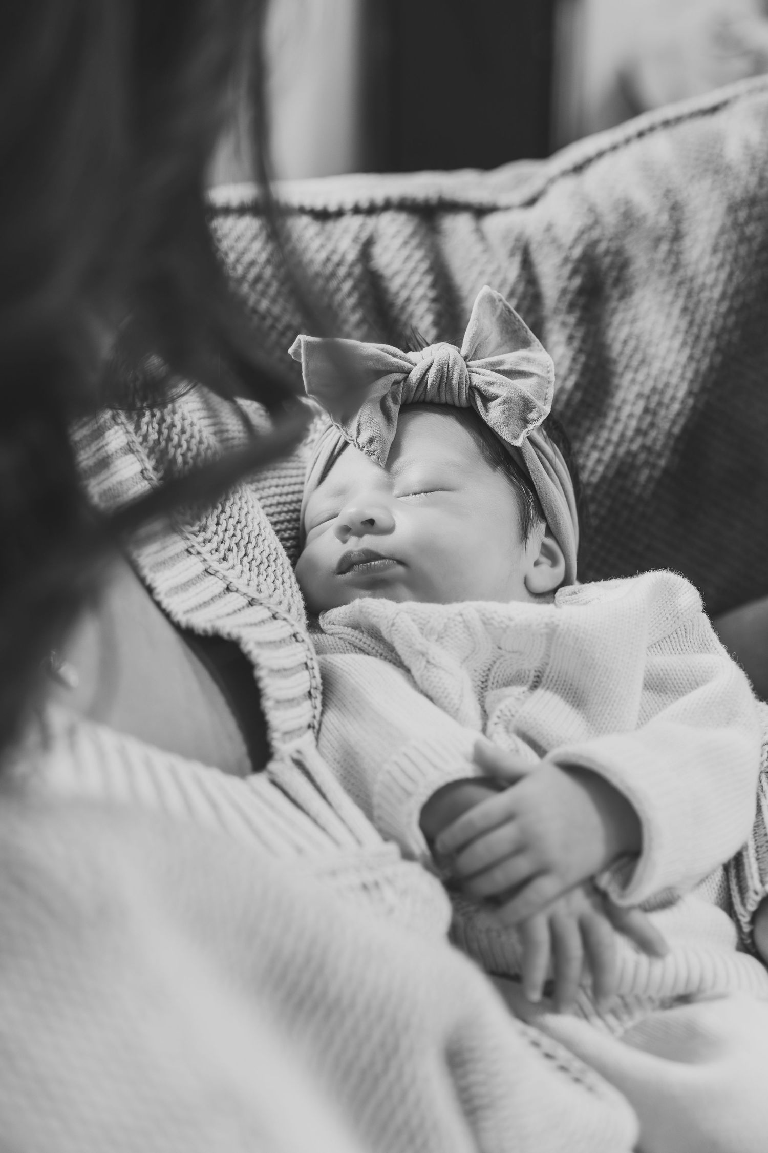 Black and white portrait of a sleeping baby wrapped in soft textured blankets.