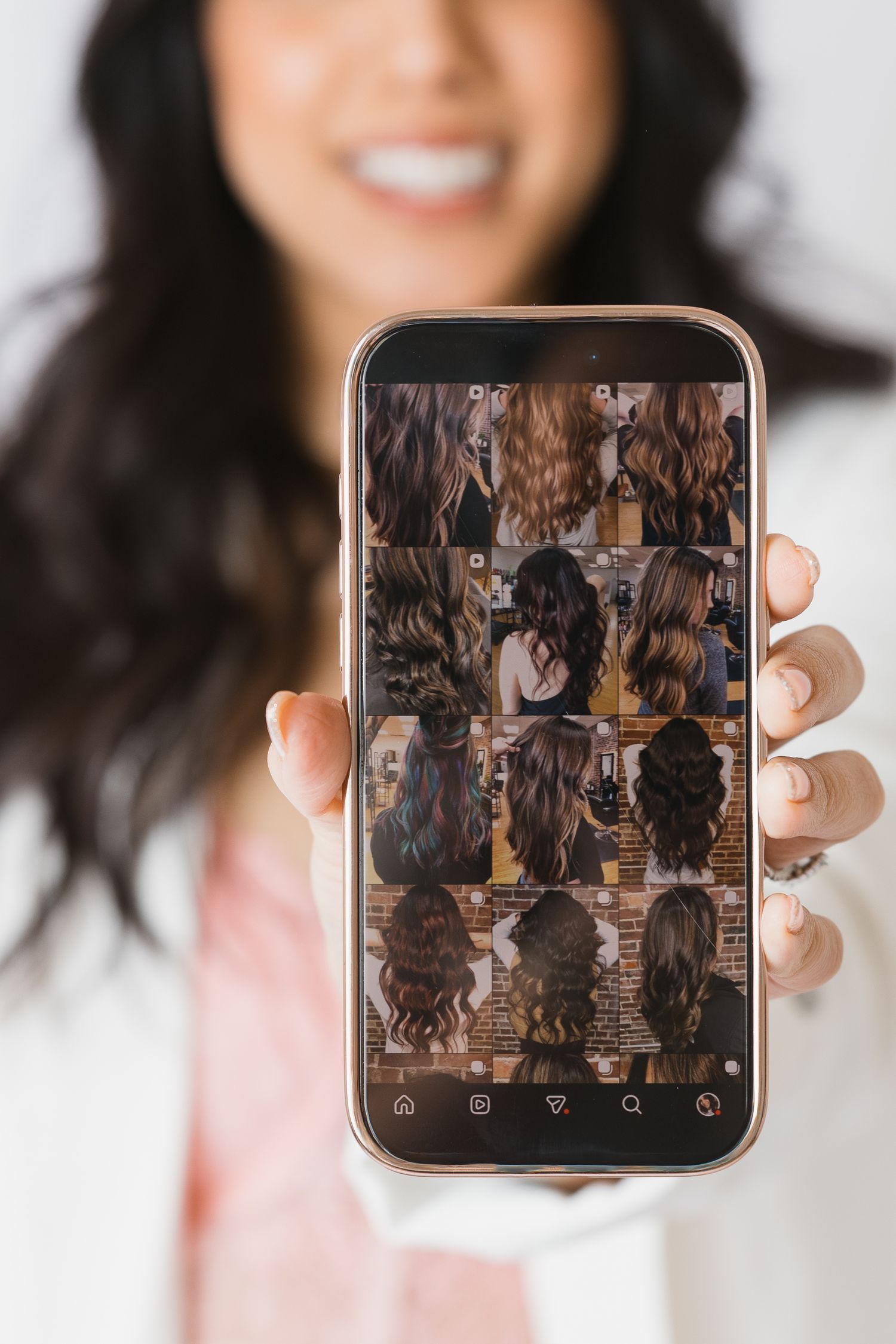 Hands holding rose gold phone displaying photo gallery interface.