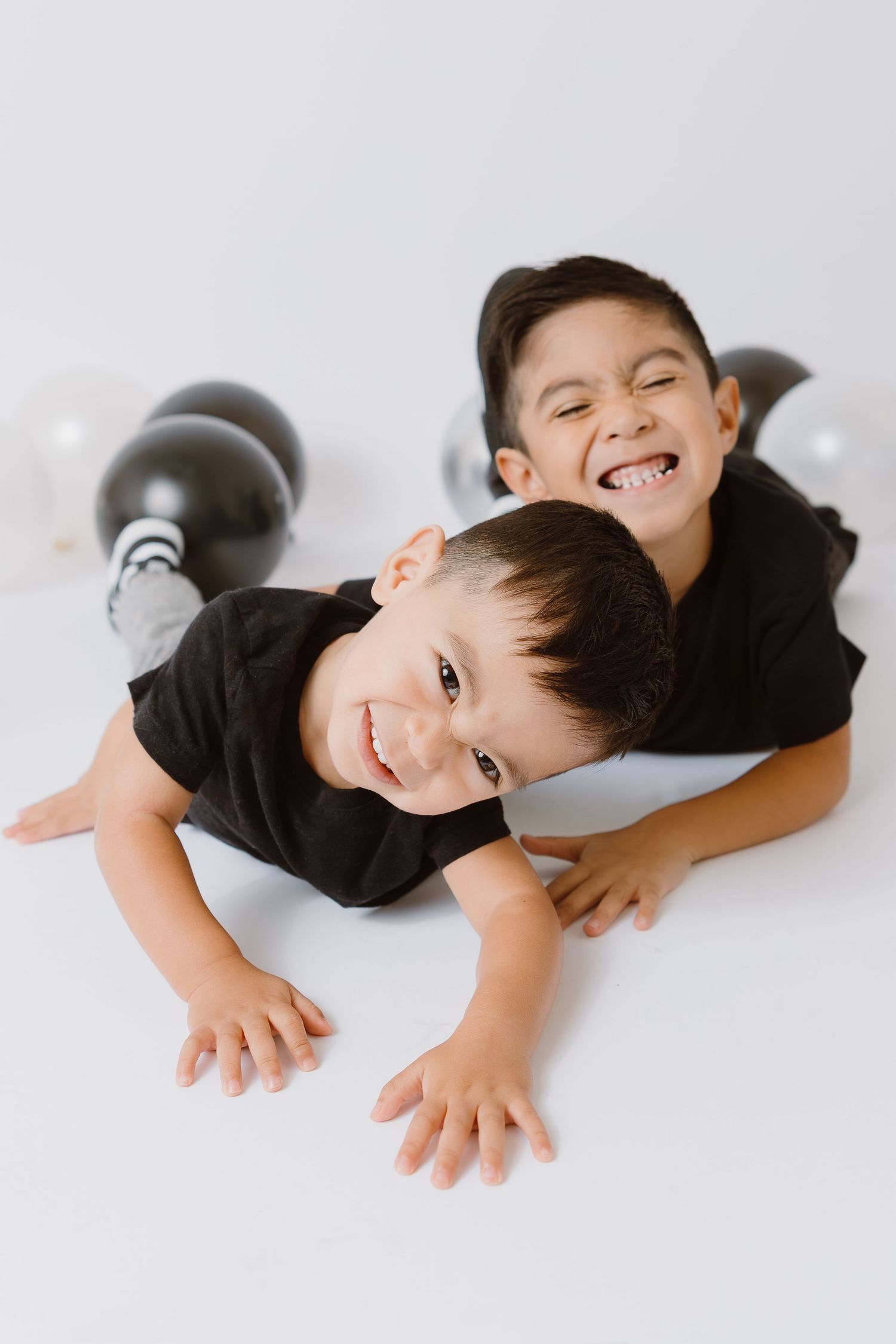 Children lying on white background playfully pose for camera.