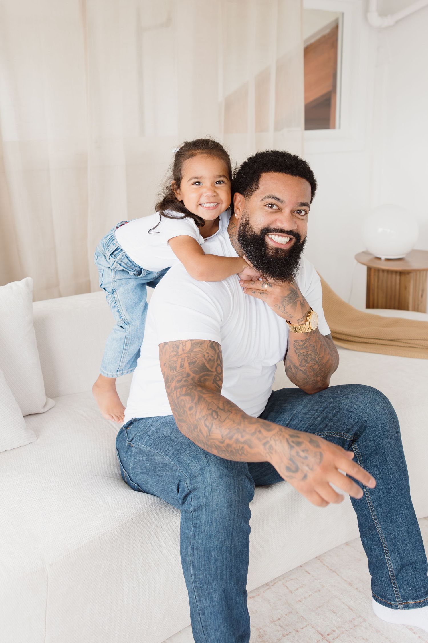 Playful moments between a couple wearing jeans and white shirts in a minimalist setting.