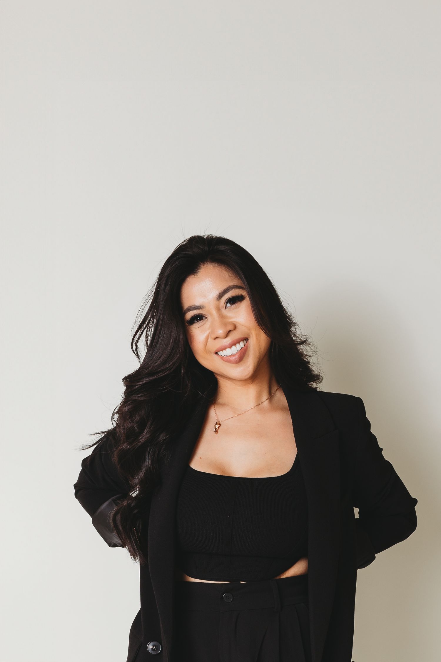 Person in black blazer and top smiling against white background.