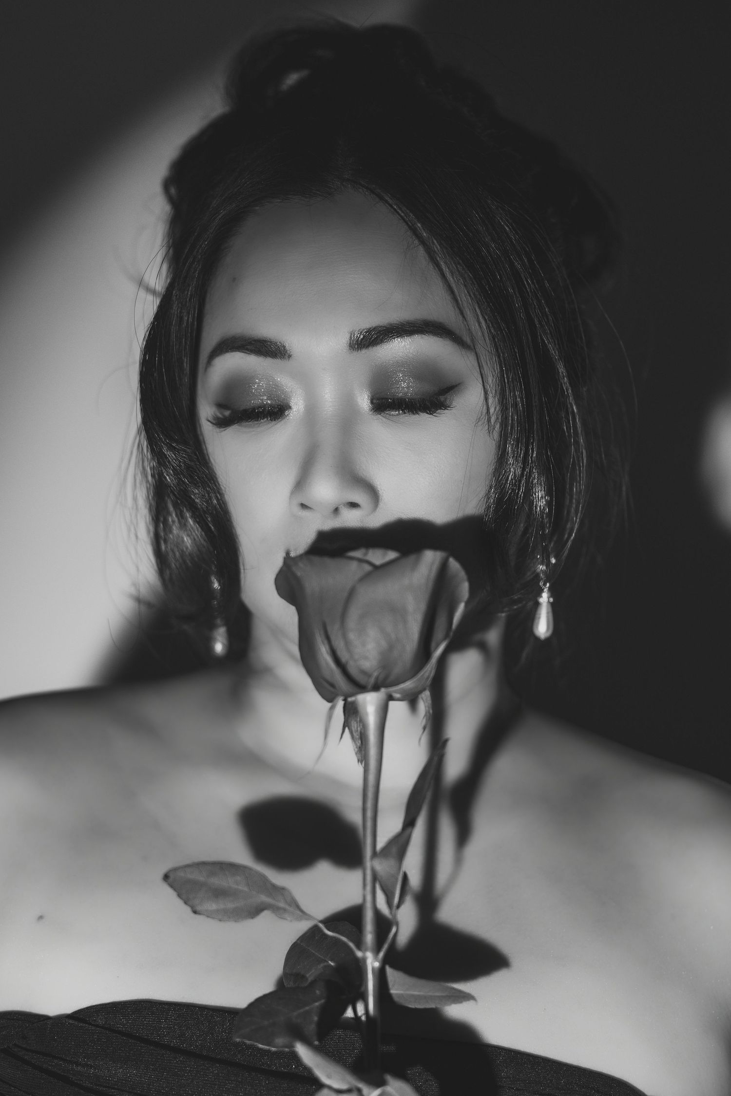 Dramatic black and white portrait with single rose and moody lighting.