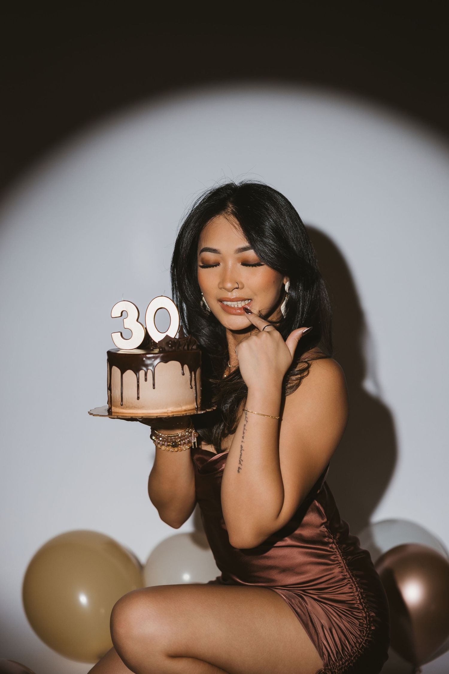 Birthday celebration photoshoot with cake and number 30 decorations in dramatic lighting.