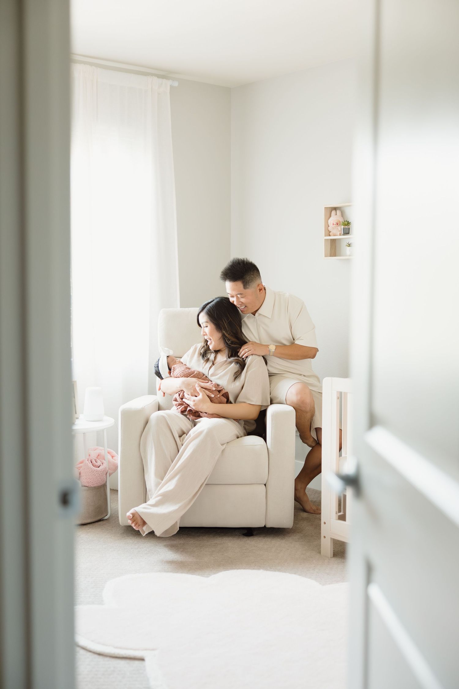 Parents sharing an intimate moment with their newborn in a bright, minimalist living room setting.