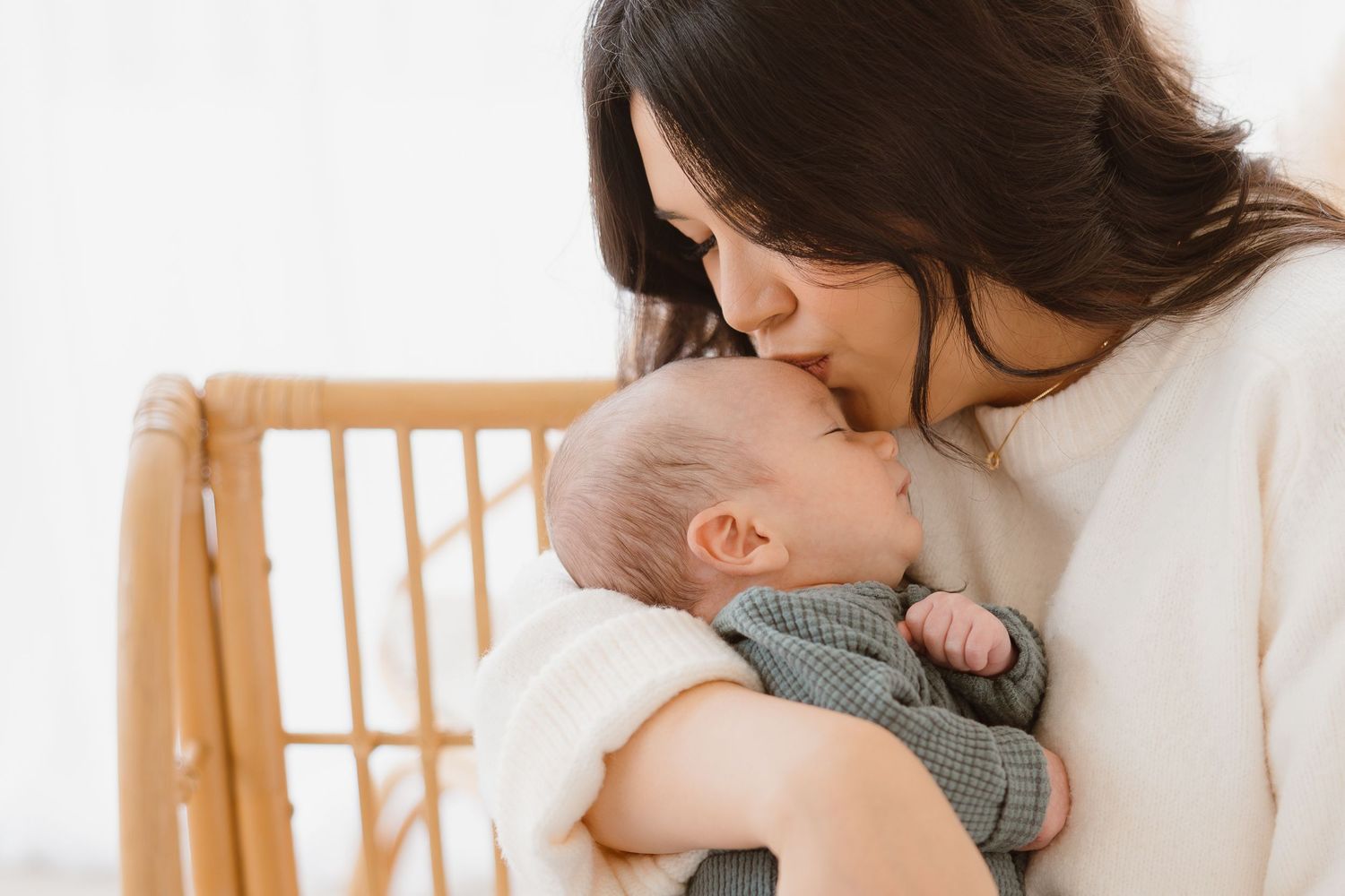 Intimate family moments captured with newborn baby in white nursery setting.