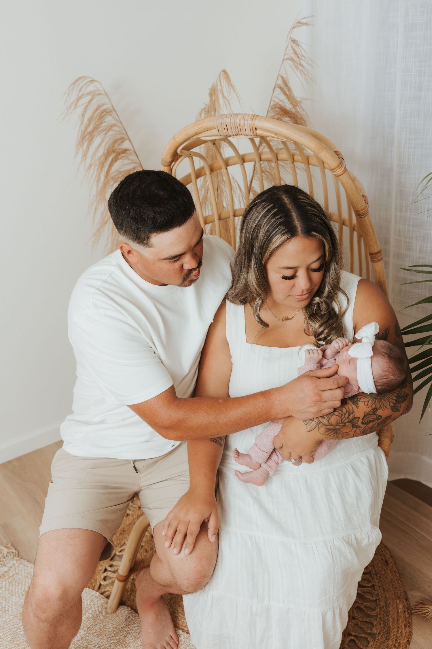 Family sharing tender moments together in white outfits on rattan furniture.