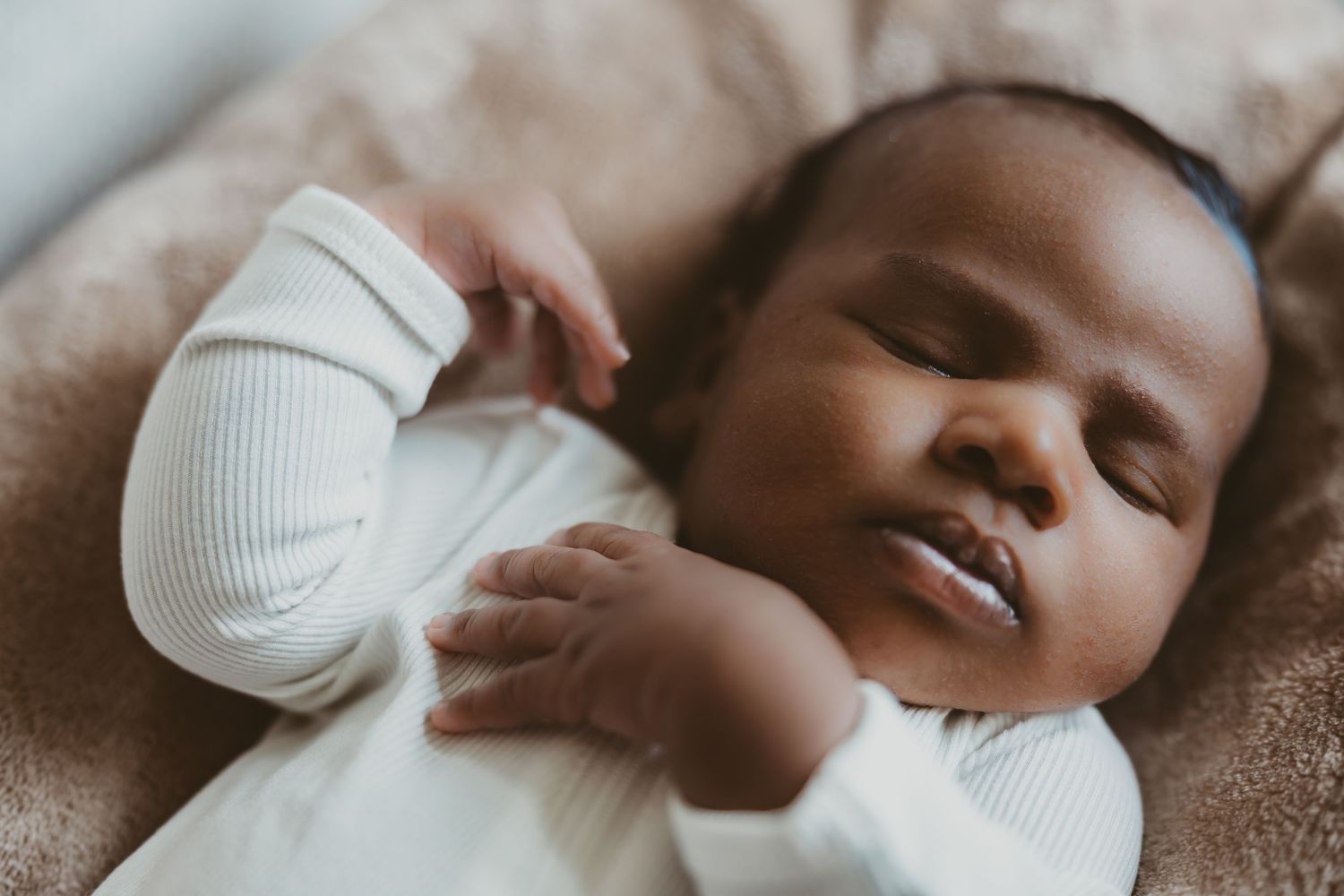 Serene close-up portrait of a sleeping infant in white clothing.