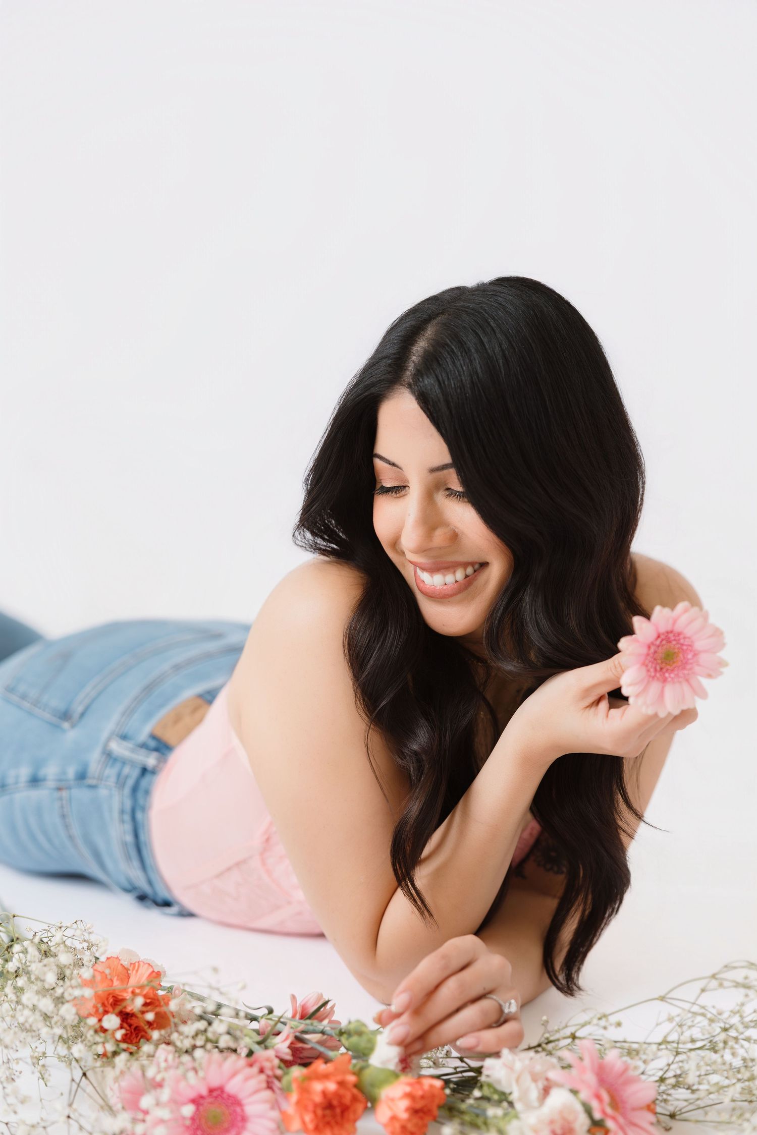Boudoir photography with pink flowers and delicate styling against white background.