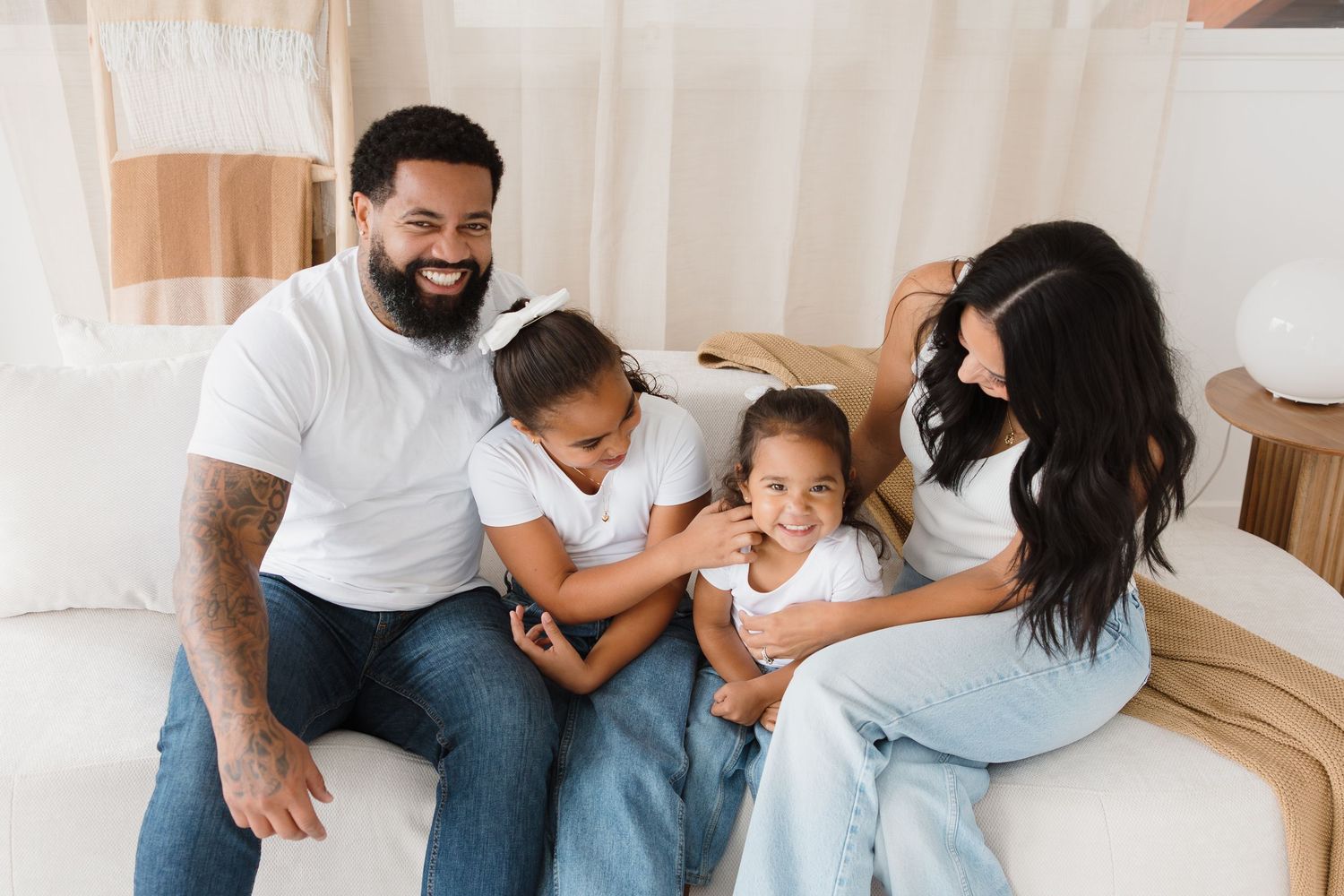 Family sharing tender moments together on white couch during lifestyle photoshoot.
