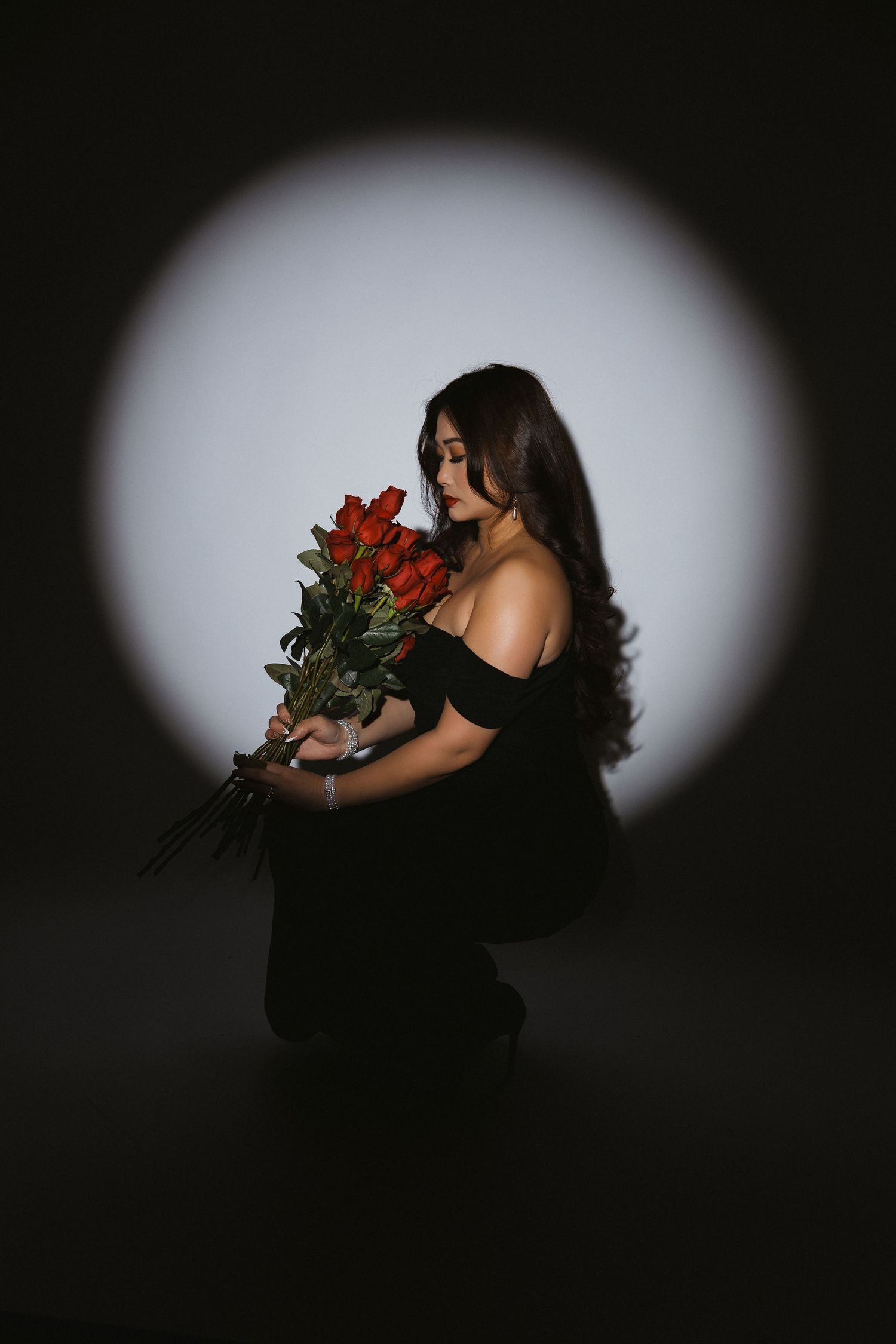 Dramatic dark portraits with red roses creating moody silhouettes against spotlight.