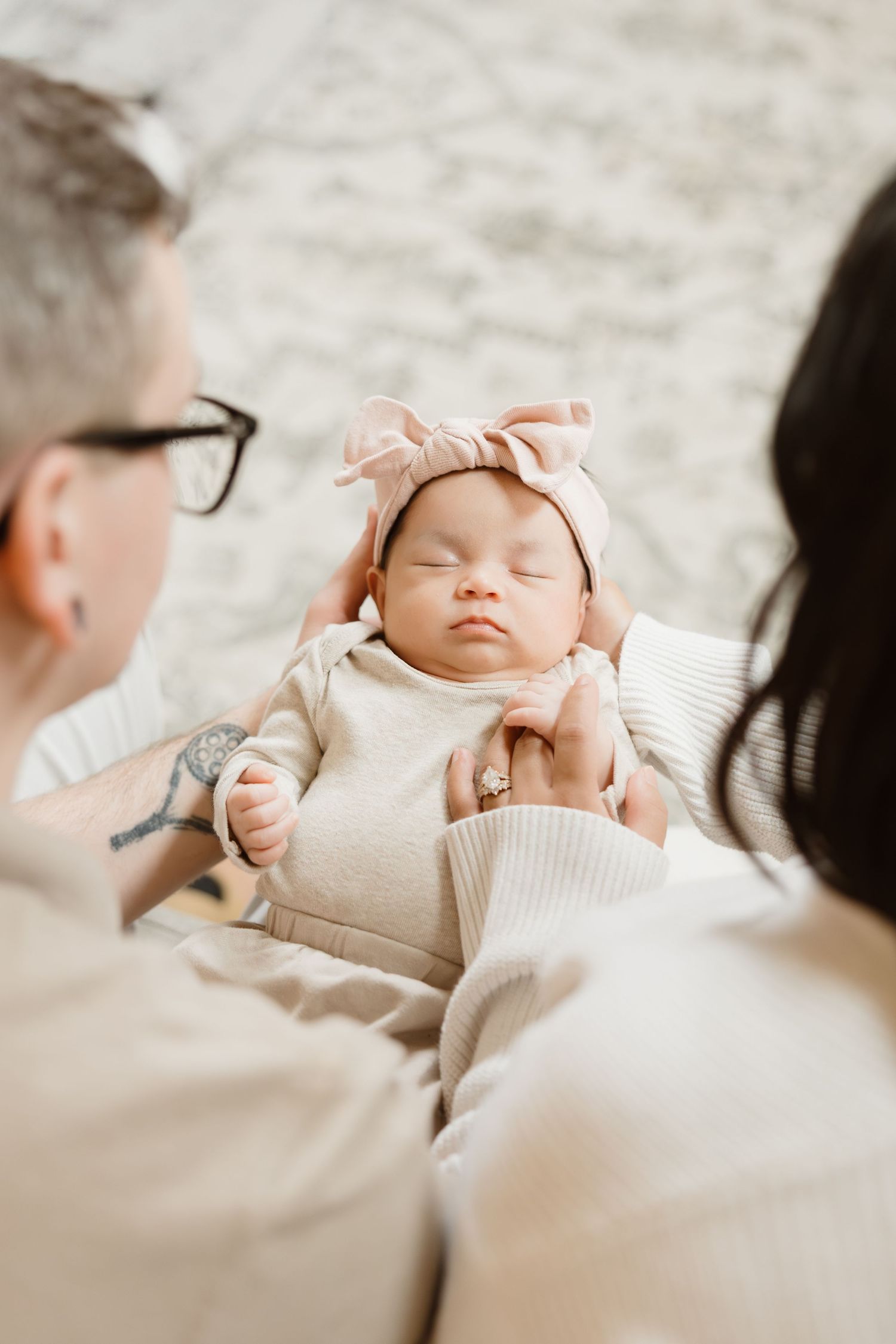 Sleeping infant wearing light colored outfit resting on soft textured surface.