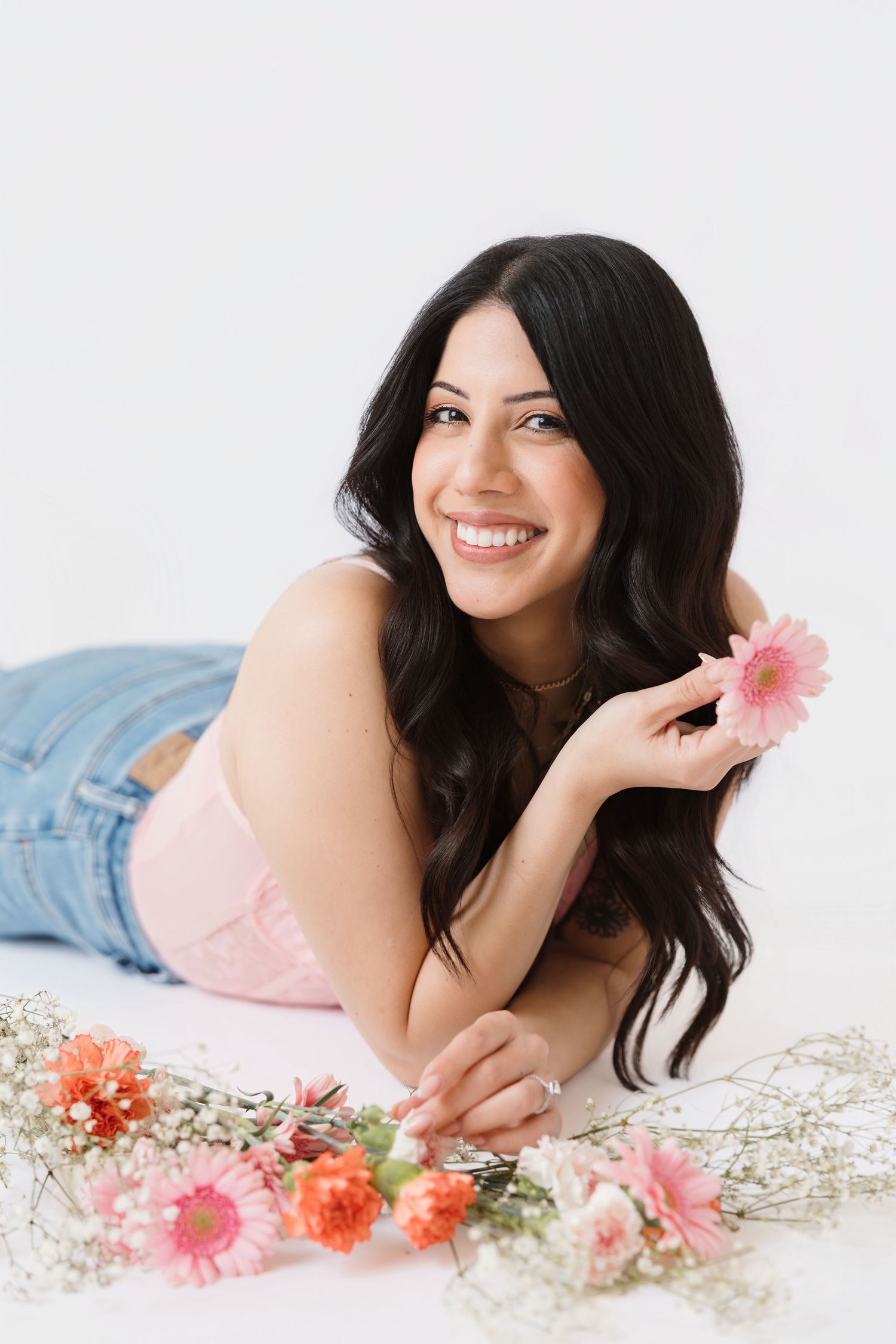 Boudoir photoshoot with pink flowers and delicate styling on white background.