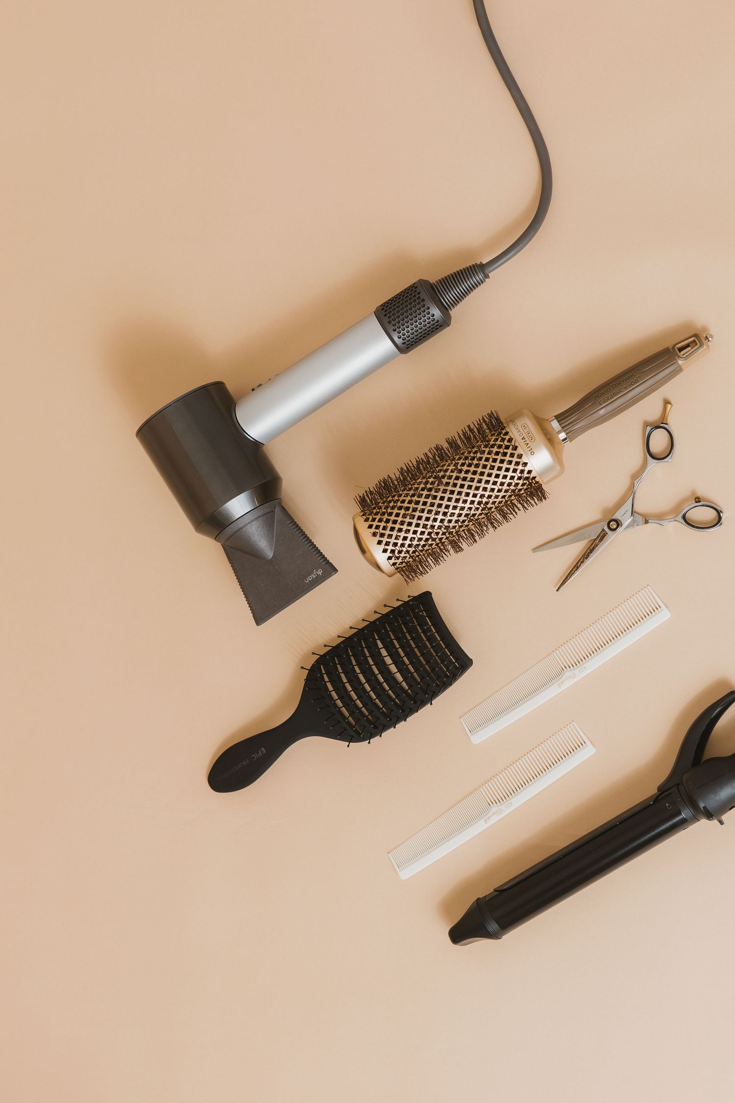 Hair styling tools and accessories arranged on beige background.