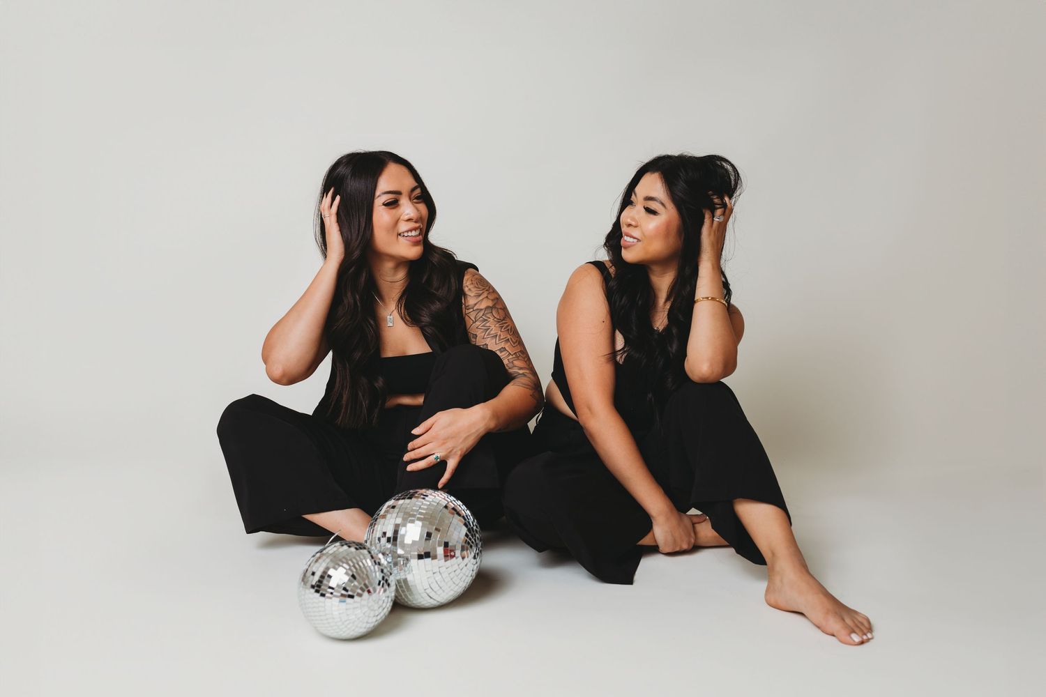 Artistic studio photoshoot with disco ball prop and black clothing on white background.
