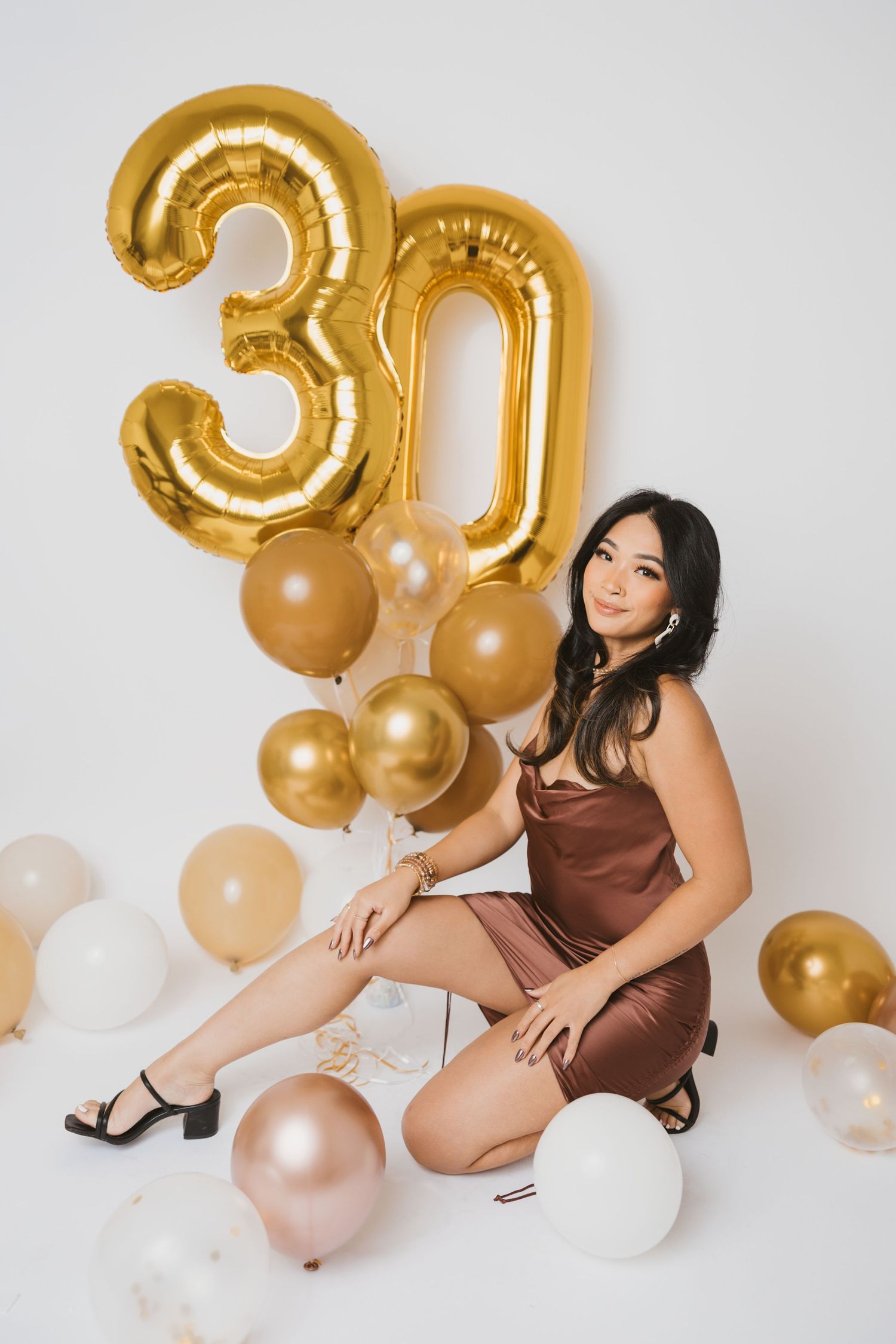 Birthday celebration setup with gold number balloons and elegant poses.