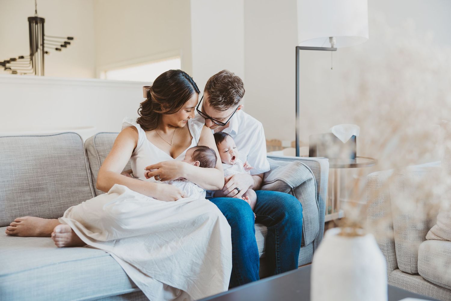 Parents sharing tender moments with their newborn on a comfortable couch.