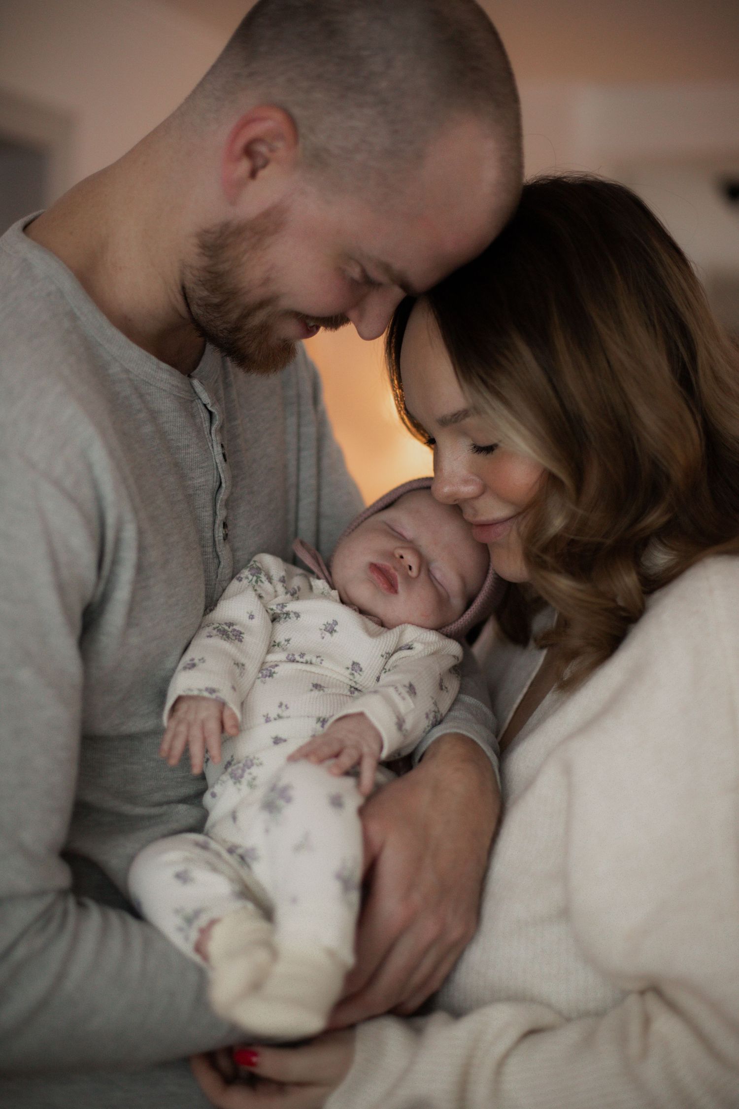 Nyfödd bebis i sina föräldrars armar vid familjefotografering.