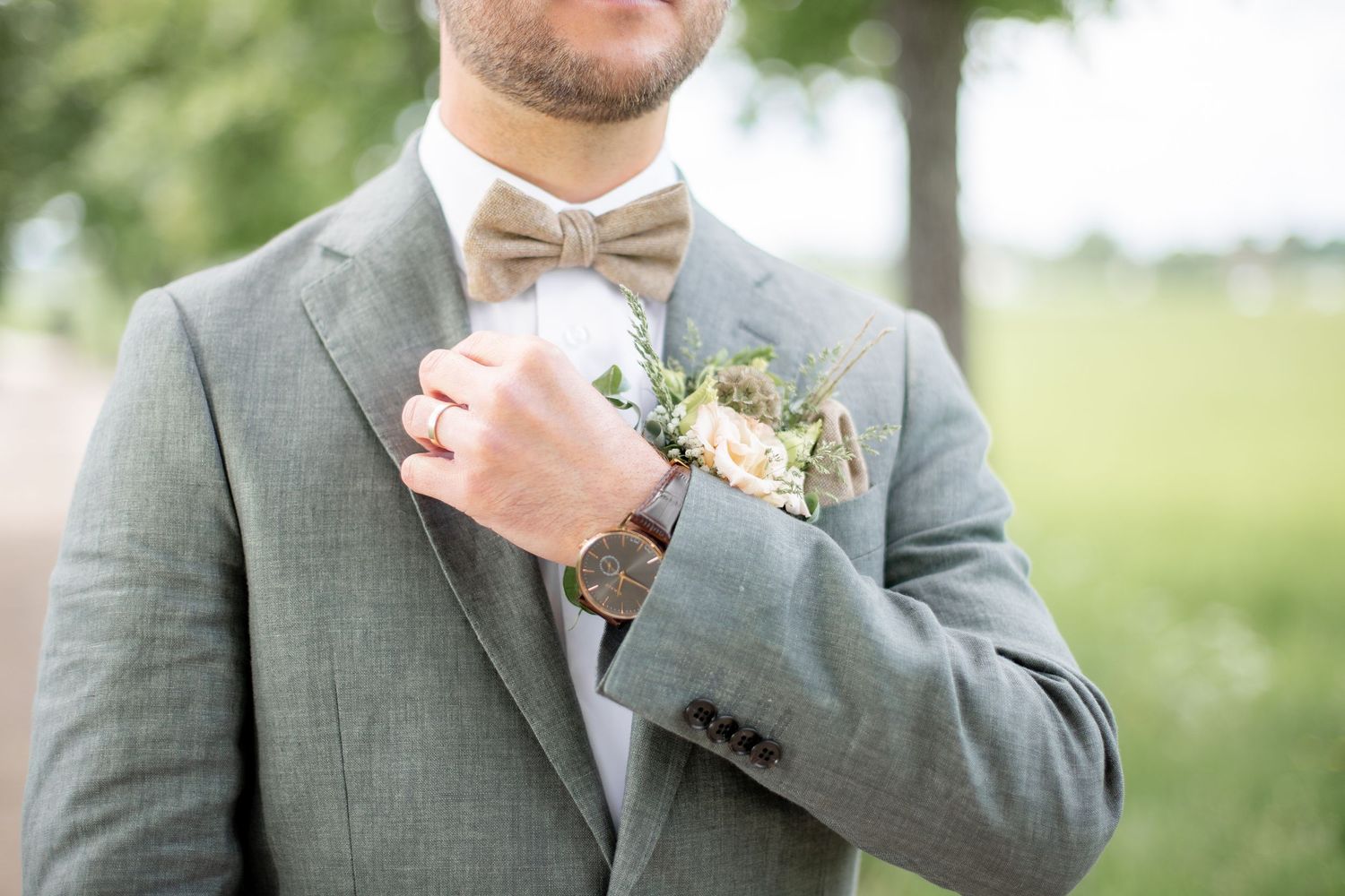 Detaljbild på brudgums fluga, kavaj, corsage, knapphålsblomma.