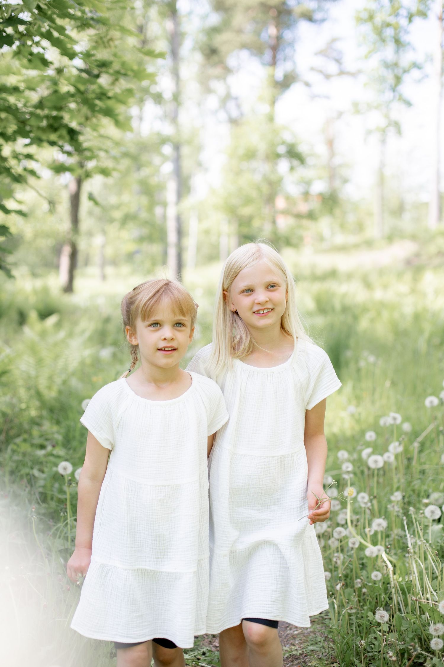 Två systrar under en familjefotografering i ängsmiljö.