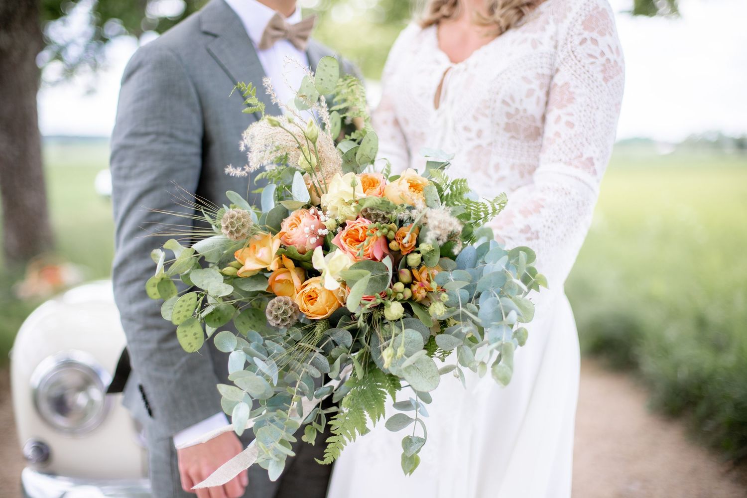 Närbild på brudbukett i grönt och aprikost med eucalyptus och rosor. Bröllopsfotograf i Katrineholm.