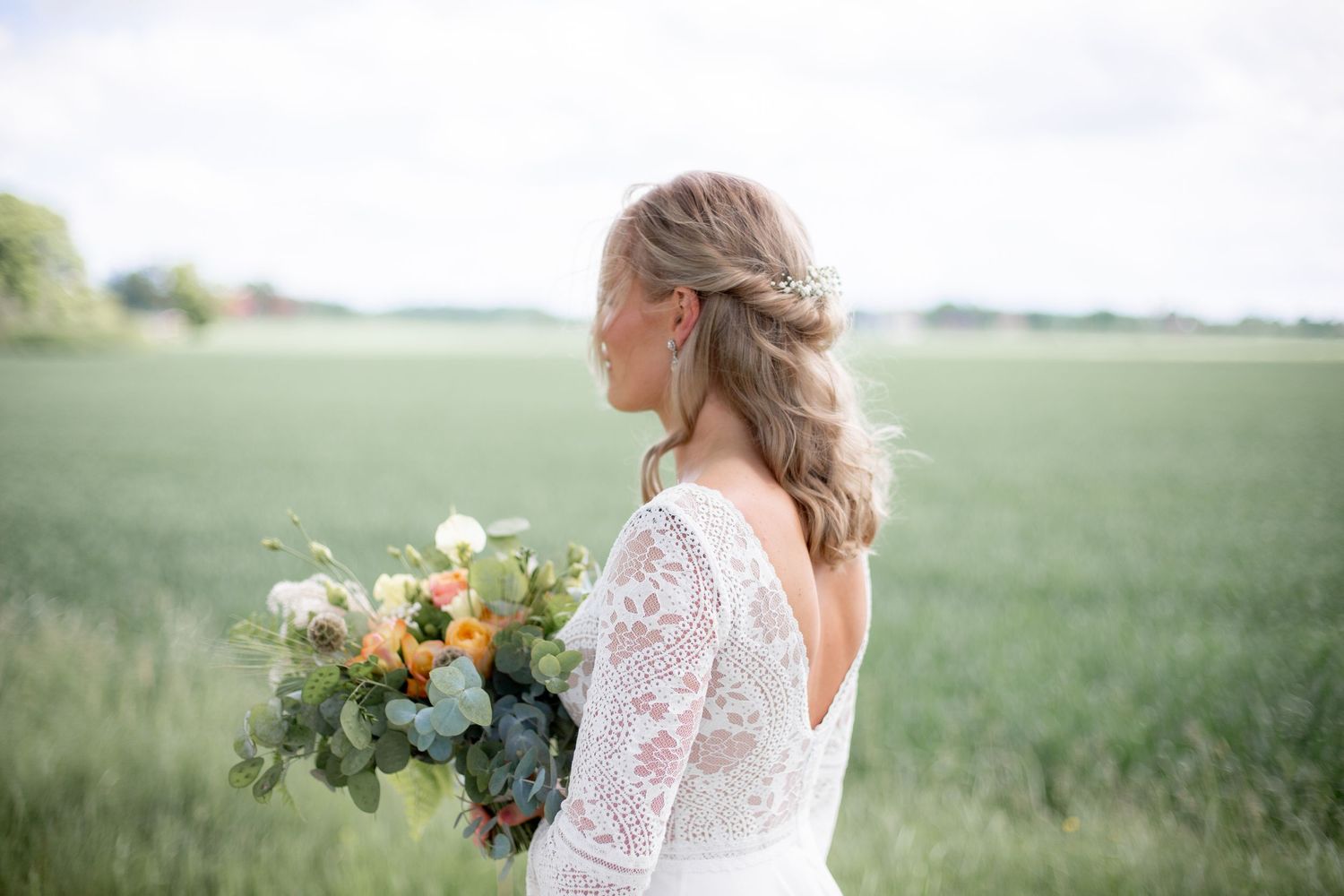 Nervös brud går mot first look med sin vackra brudbukett och bröllopsklänning. Bröllopsfotografering i Vingåker.