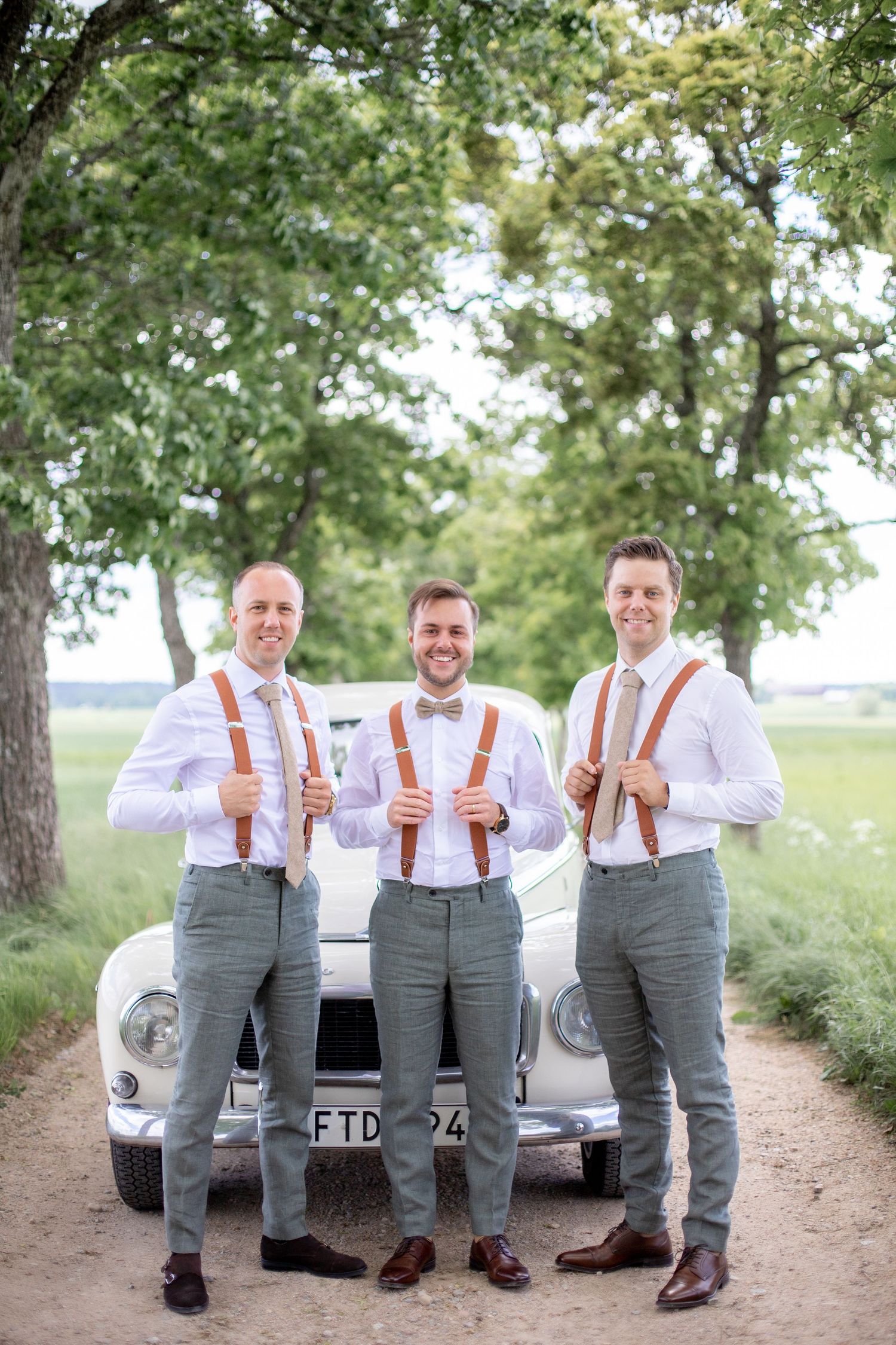 Brudgum och hans best mans under porträttfotografering. Bröllopsfotografering en solig junidag.