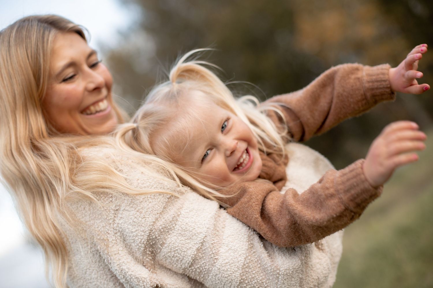Mamma lyfter barn flygande som skrattar under en familjefotografering.
