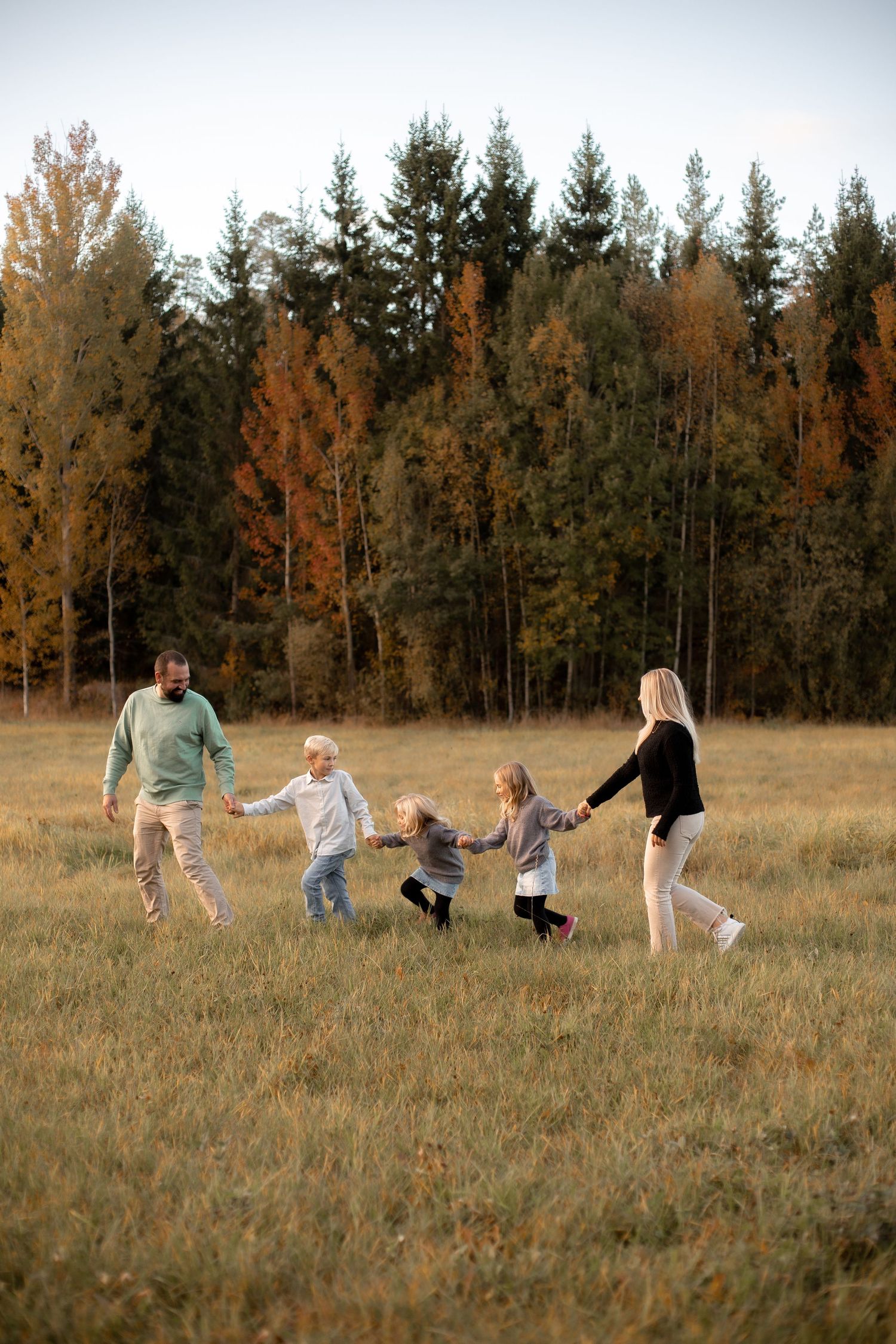 Familj på promenad i solnedgång på ett fält. Familjefotografering i Katrineholm.