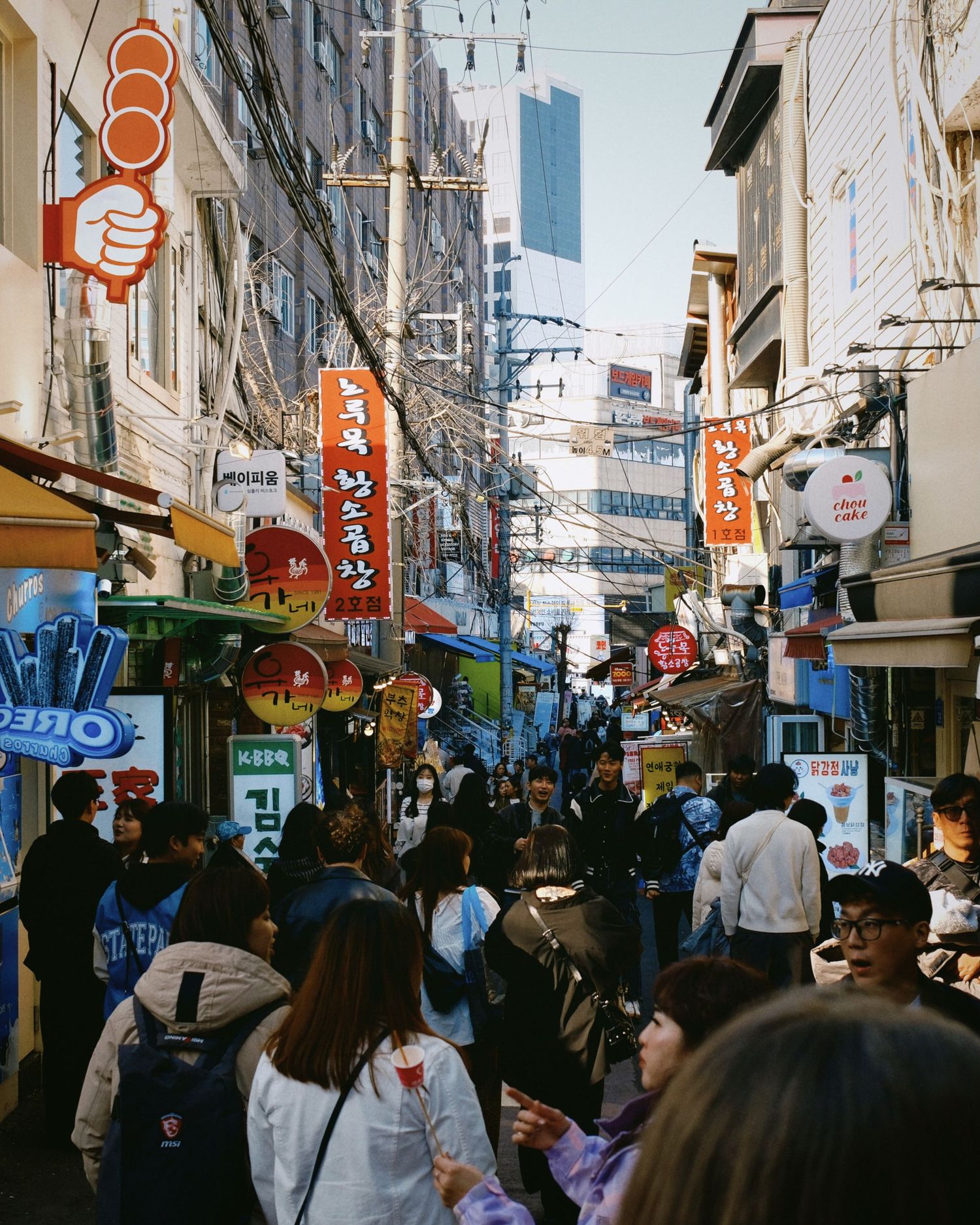 Busy street scene in an Asian shopping district with colorful signs and crowded sidewalks.