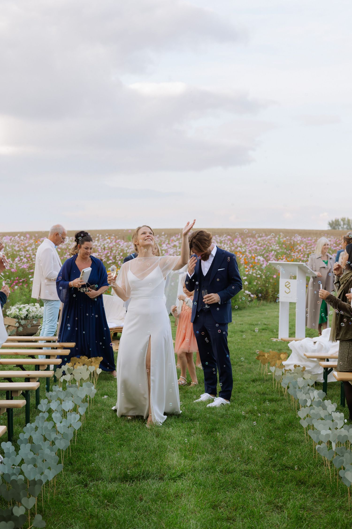 Wedding celebration on grass field with decorative elements and guests in attendance.