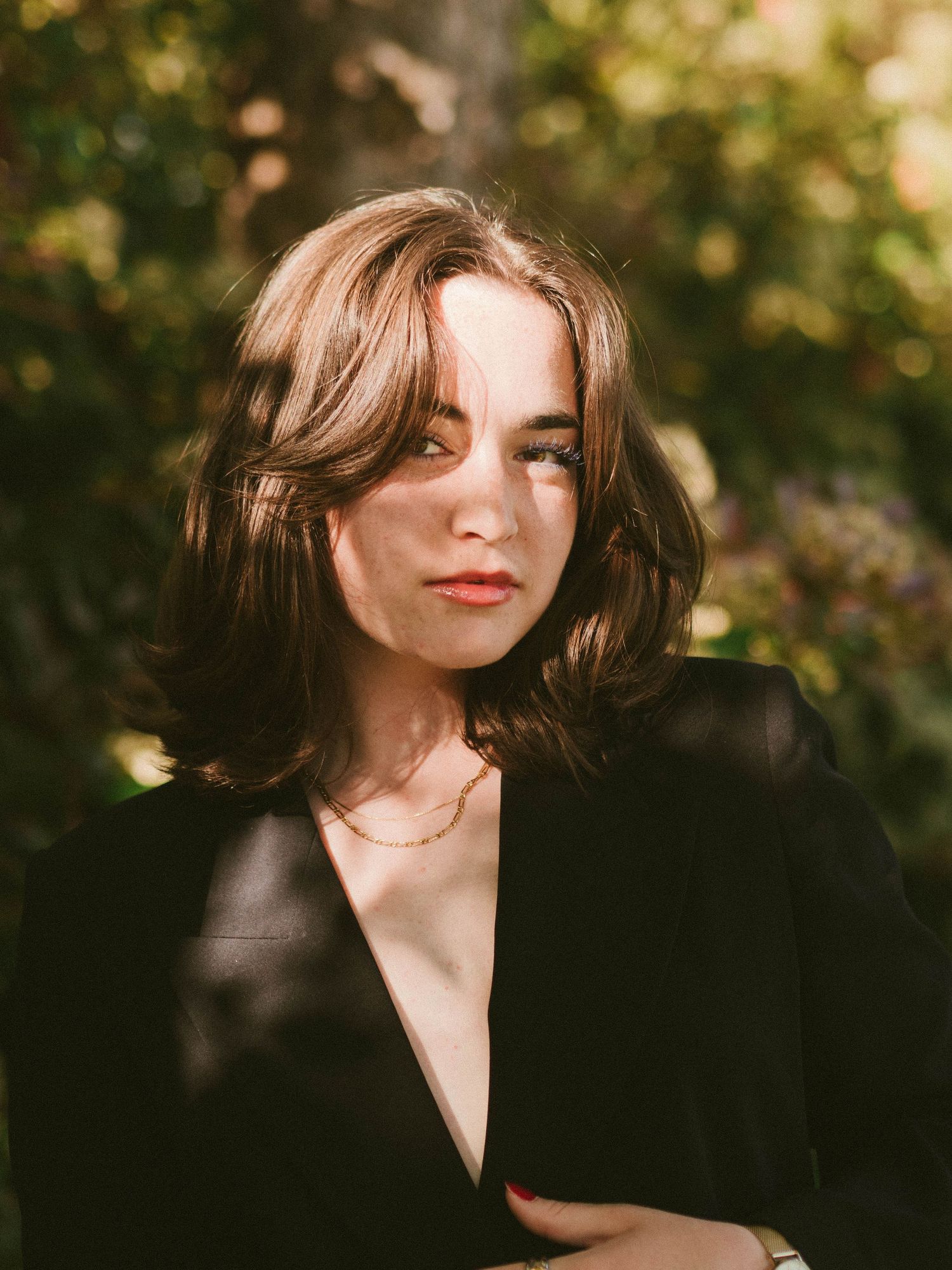 Artistic outdoor portraits with natural lighting and black clothing against a blurred background.