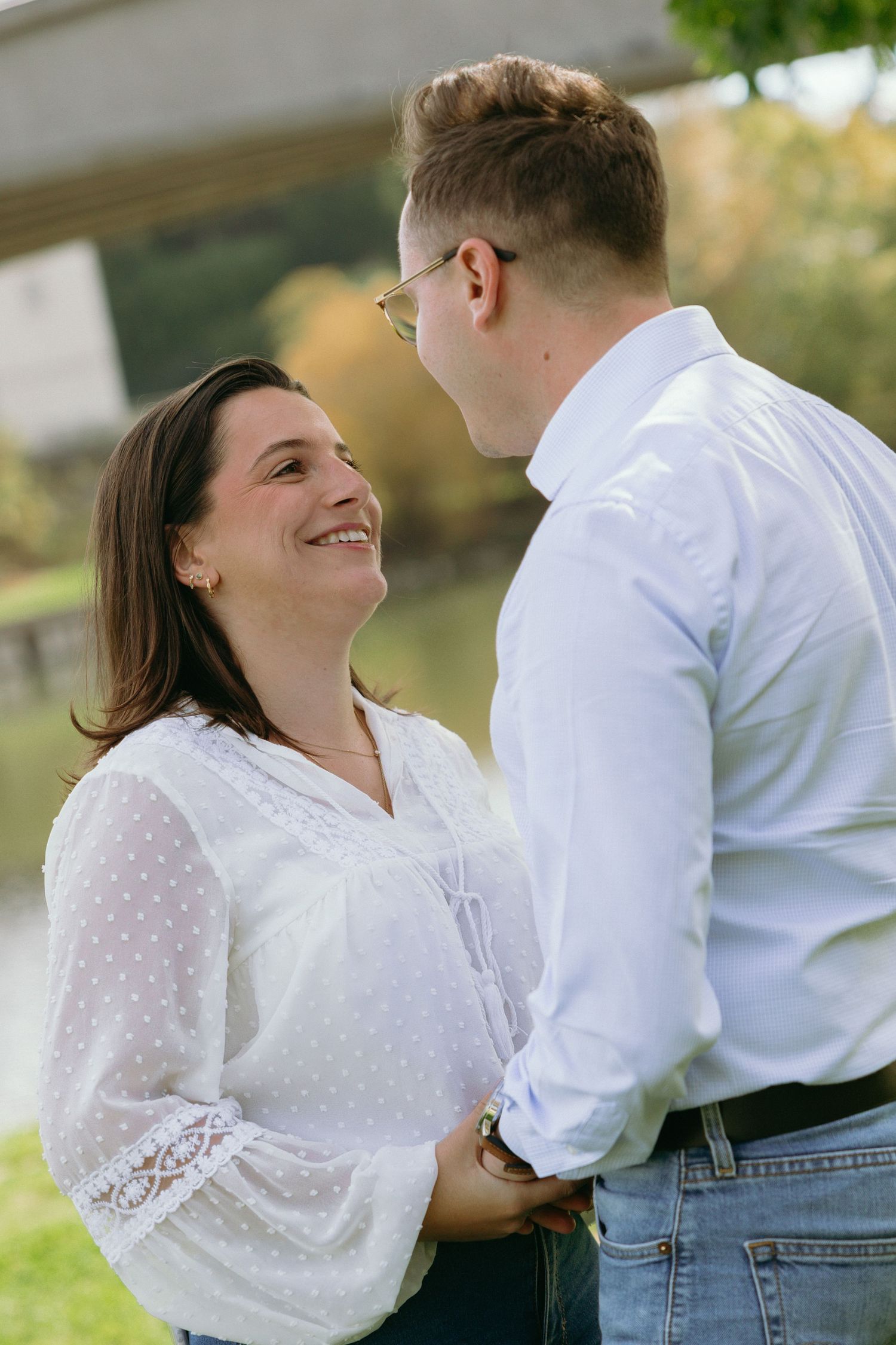 A couple shares a romantic moment outdoors in matching white outfits.