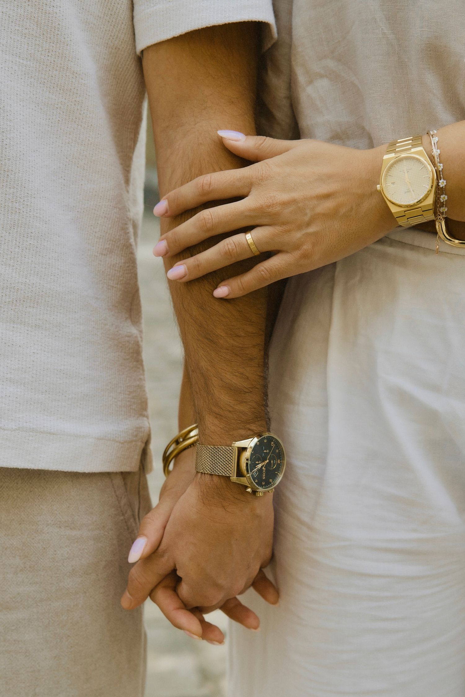 Close-up of hands wearing gold watches and rings showing an intimate moment.