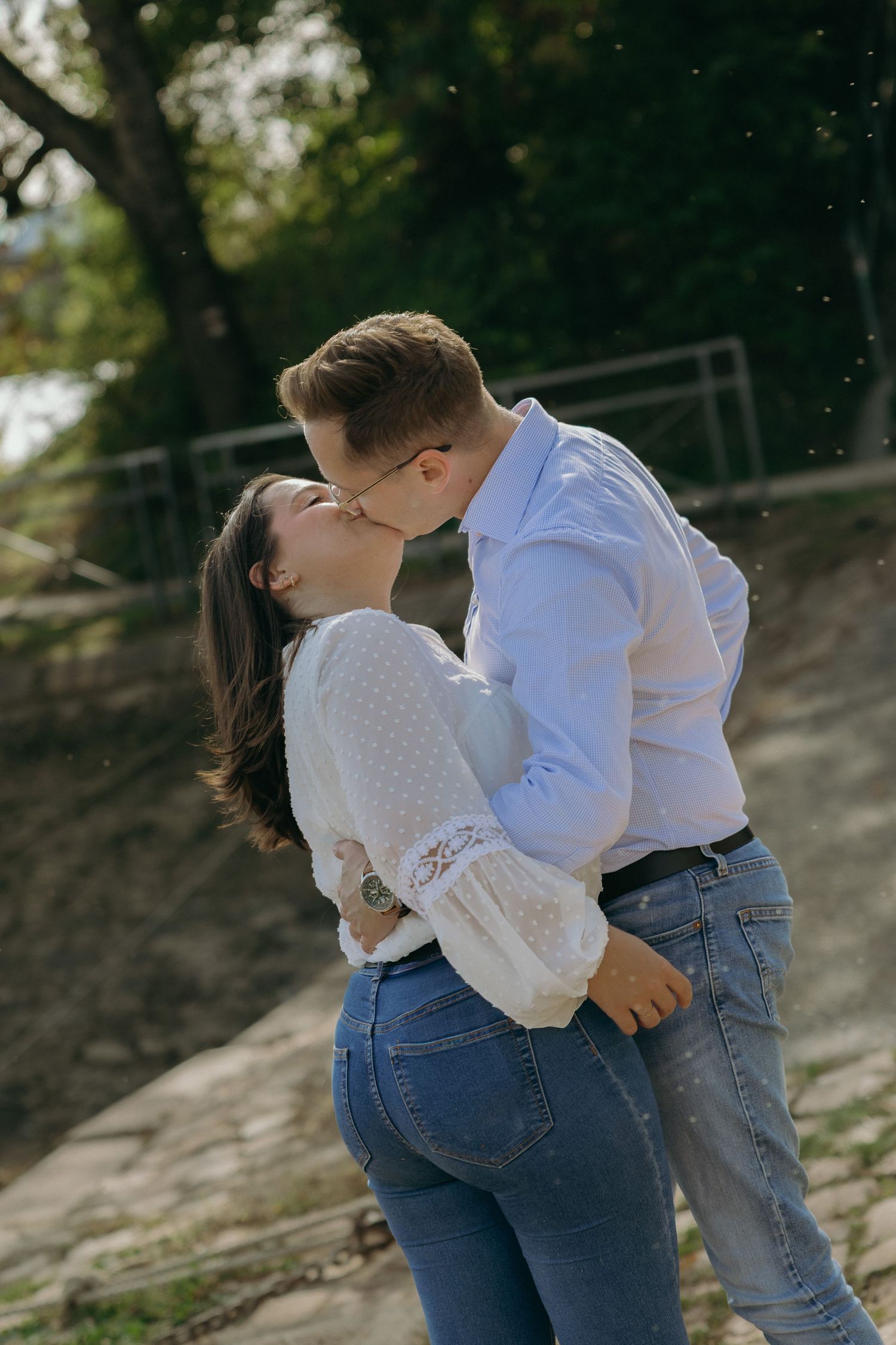 A romantic couple in casual attire shares an intimate moment outdoors.
