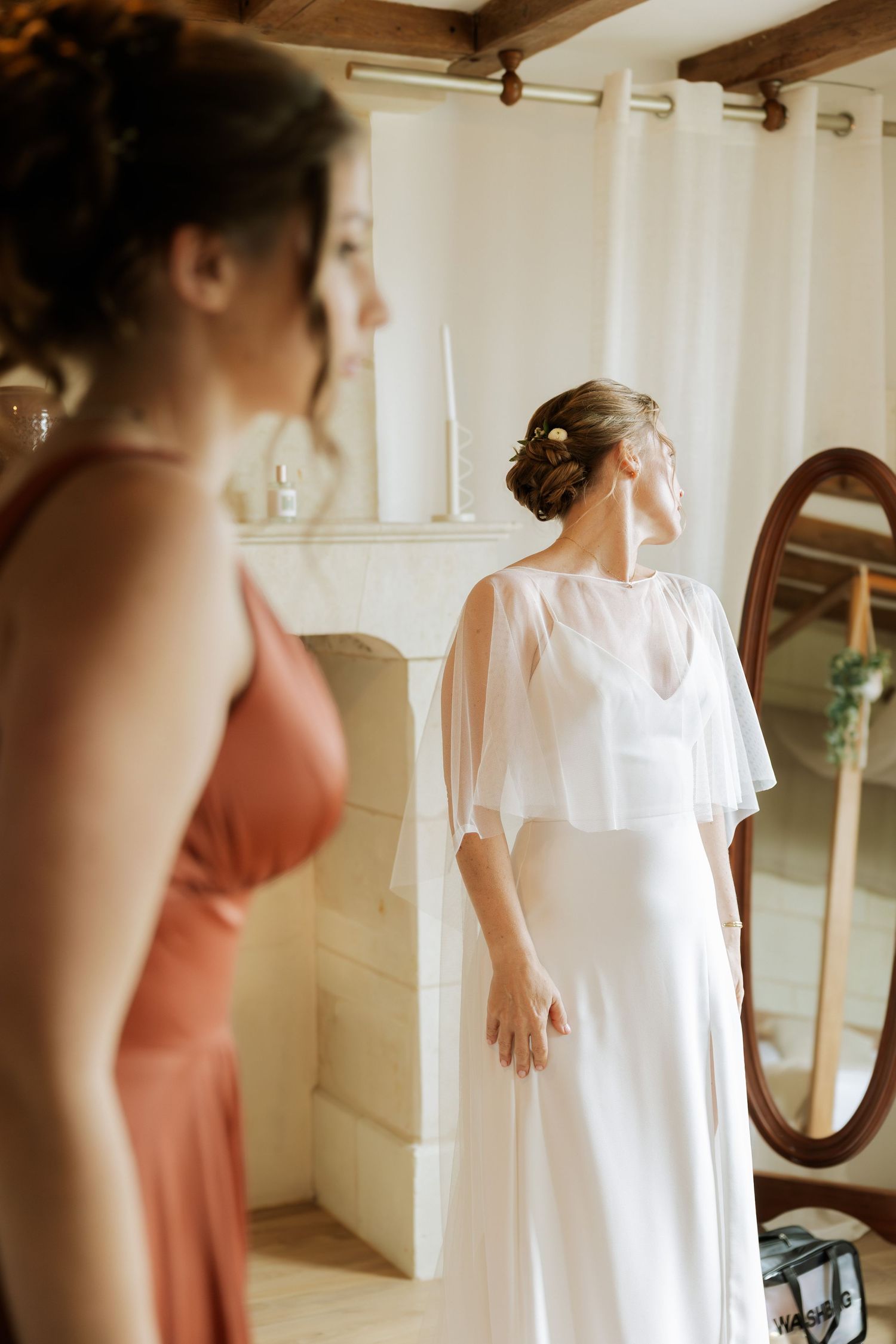 Robe de mariée blanche suspendue avec robes corail de demoiselles d’honneur en arrière-plan