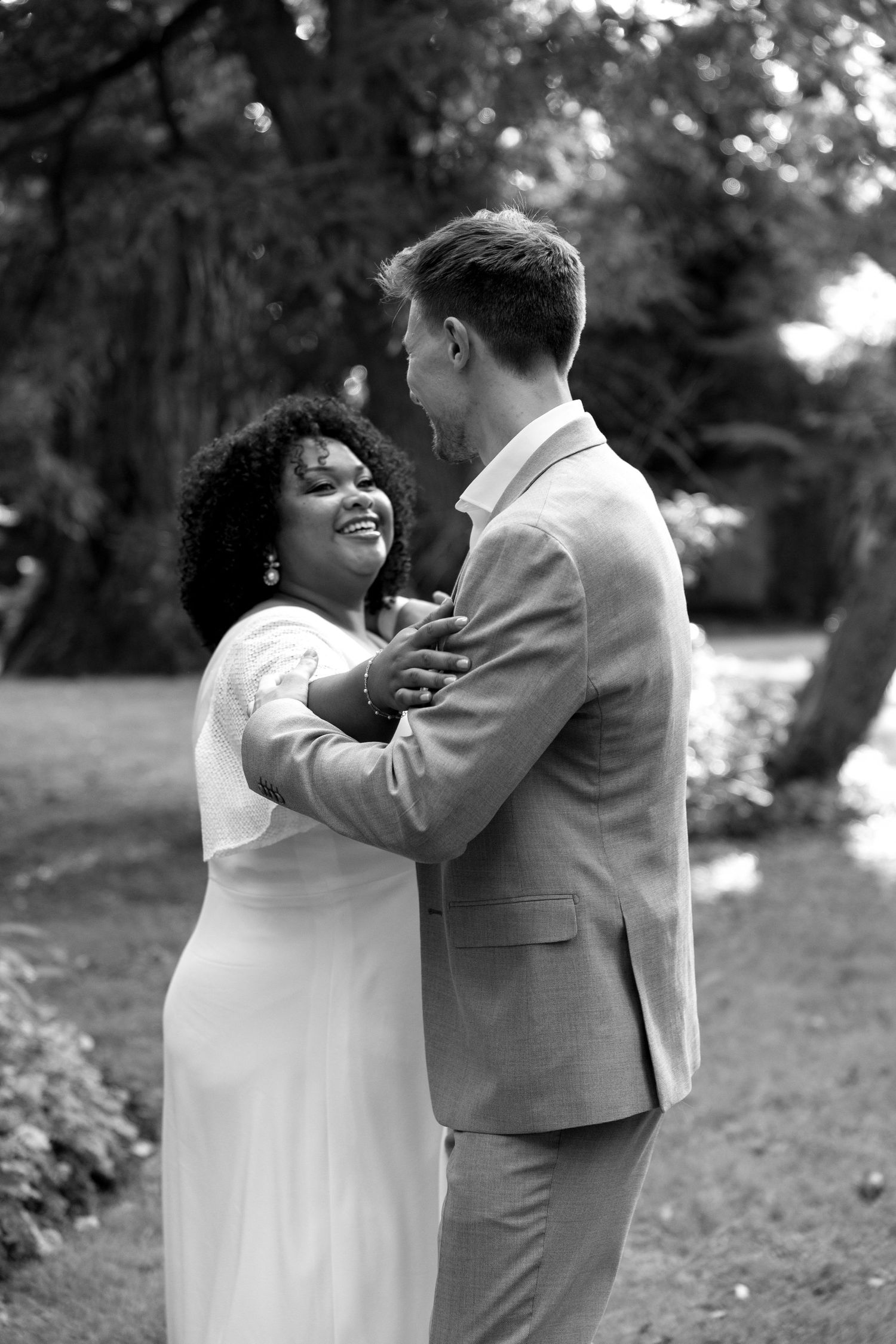 A couple shares a joyful moment together outdoors in black and white photography.