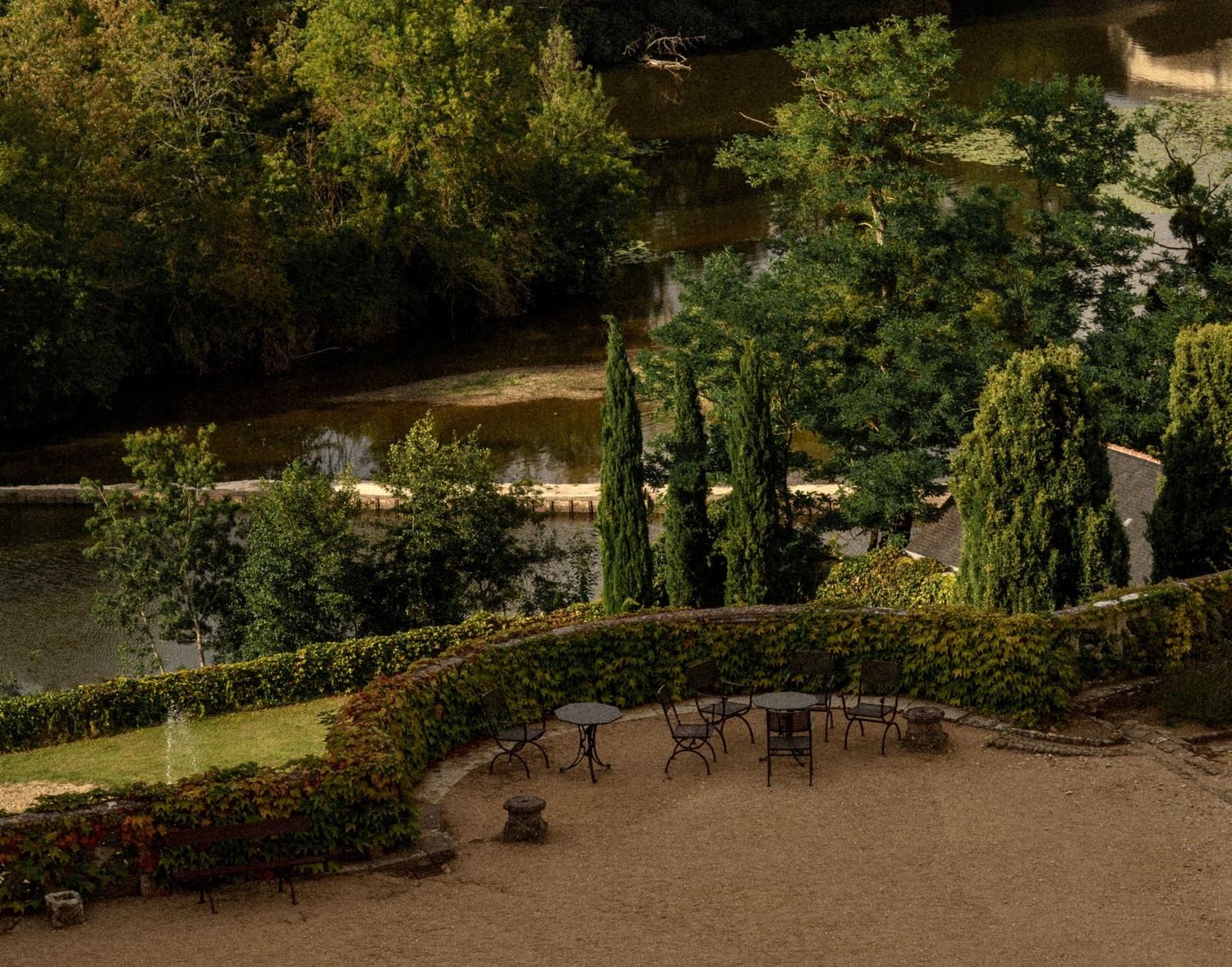 Garden terrace with stone walls and benches surrounded by lush greenery.