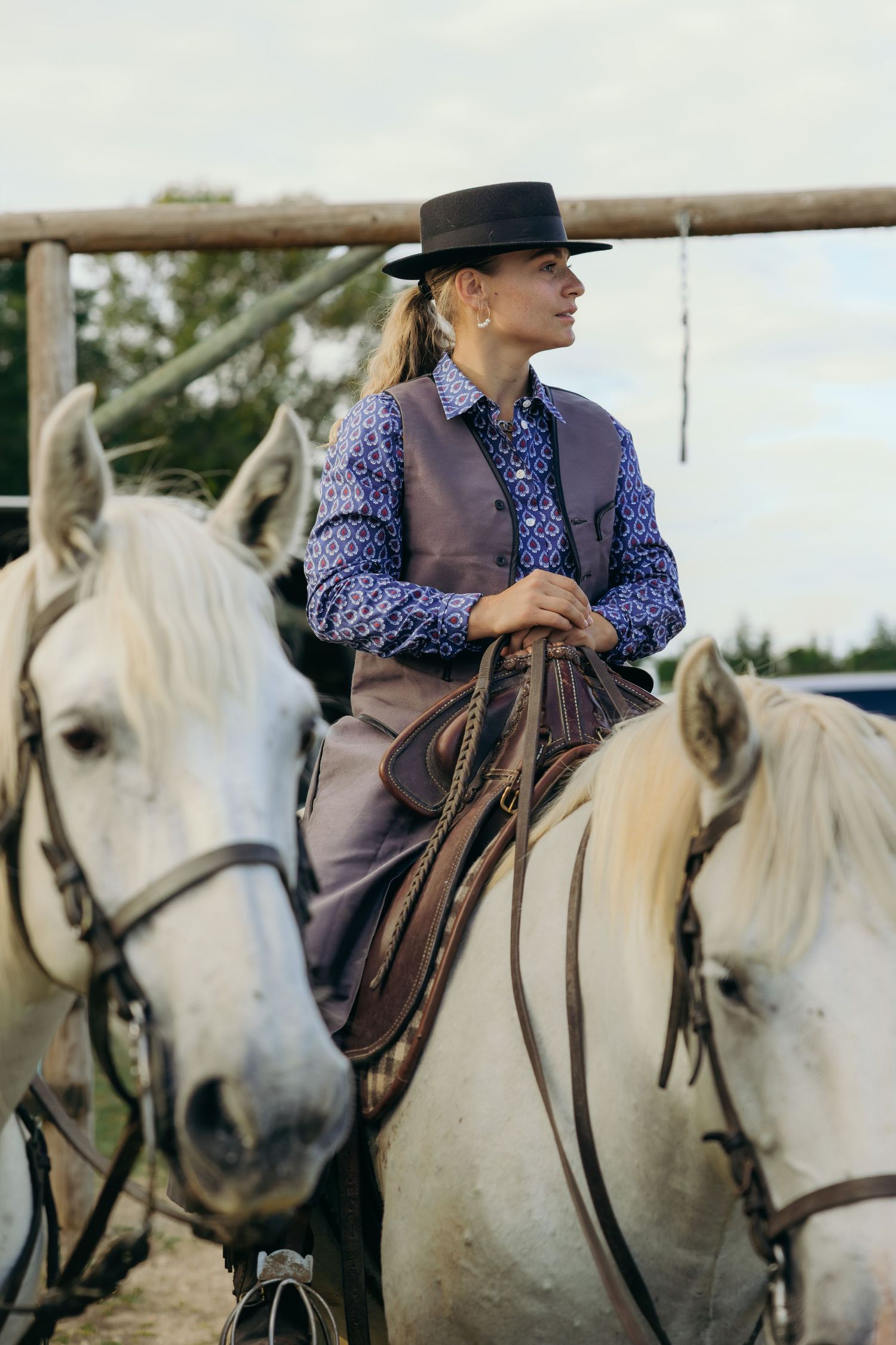 A rider in western attire sits confidently on a white horse wearing traditional tack and saddle.