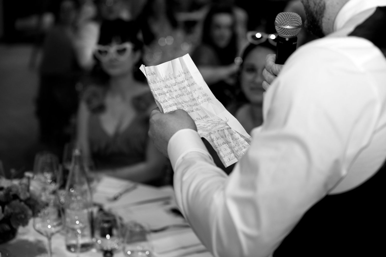 Invités d’un mariage capturés en noir et blanc pendant les discours et les toasts