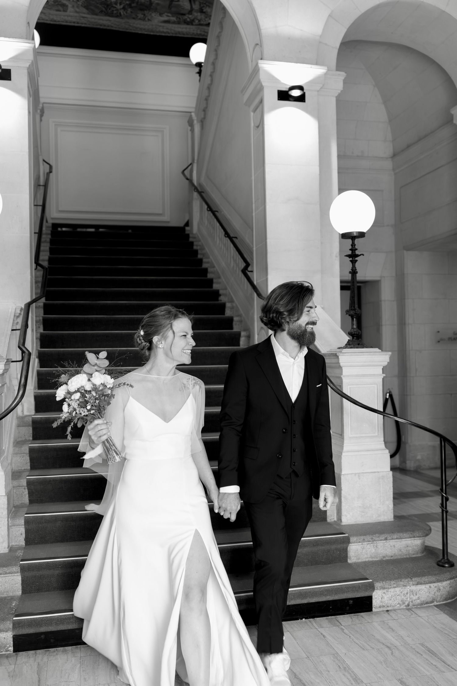 Photographie en noir et blanc capturant des moments classiques de mariage dans un hall élégant avec escalier. mairie d'angers