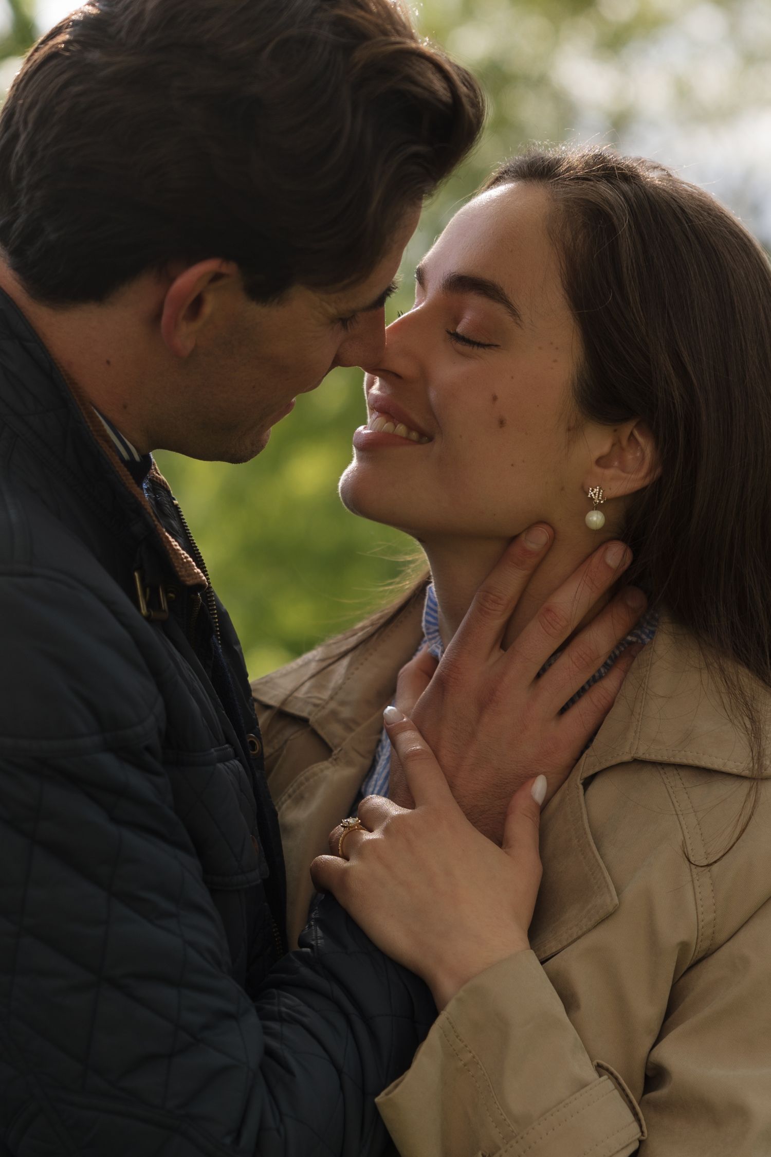 Romantic couple sharing an intimate moment outdoors, man gently holding woman's face as she smiles with eyes closed.