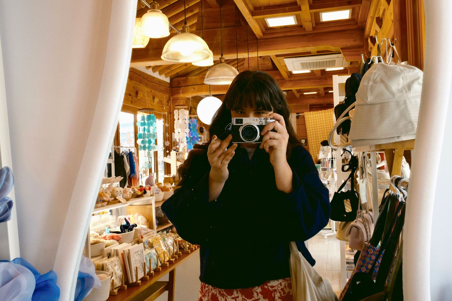 Person taking a mirror selfie with a vintage camera in a rustic wooden shop interior.