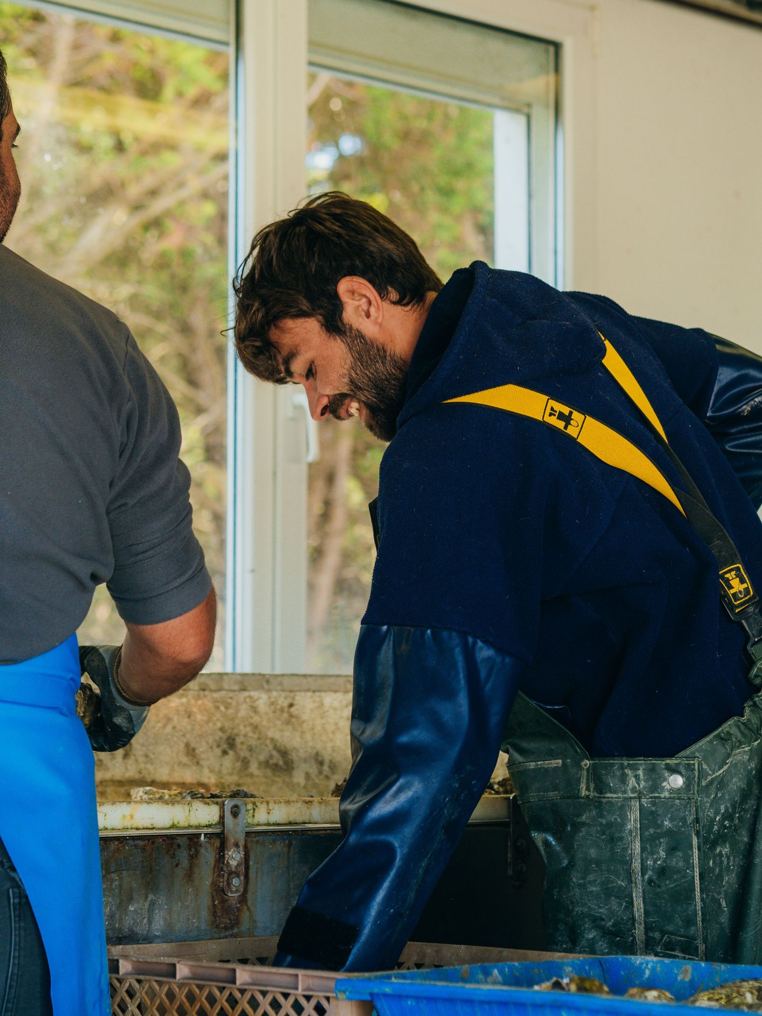 Employé ostréicole au travail, triant et préparant des huîtres dans une exploitation. Image professionnelle valorisant le savoir-faire local