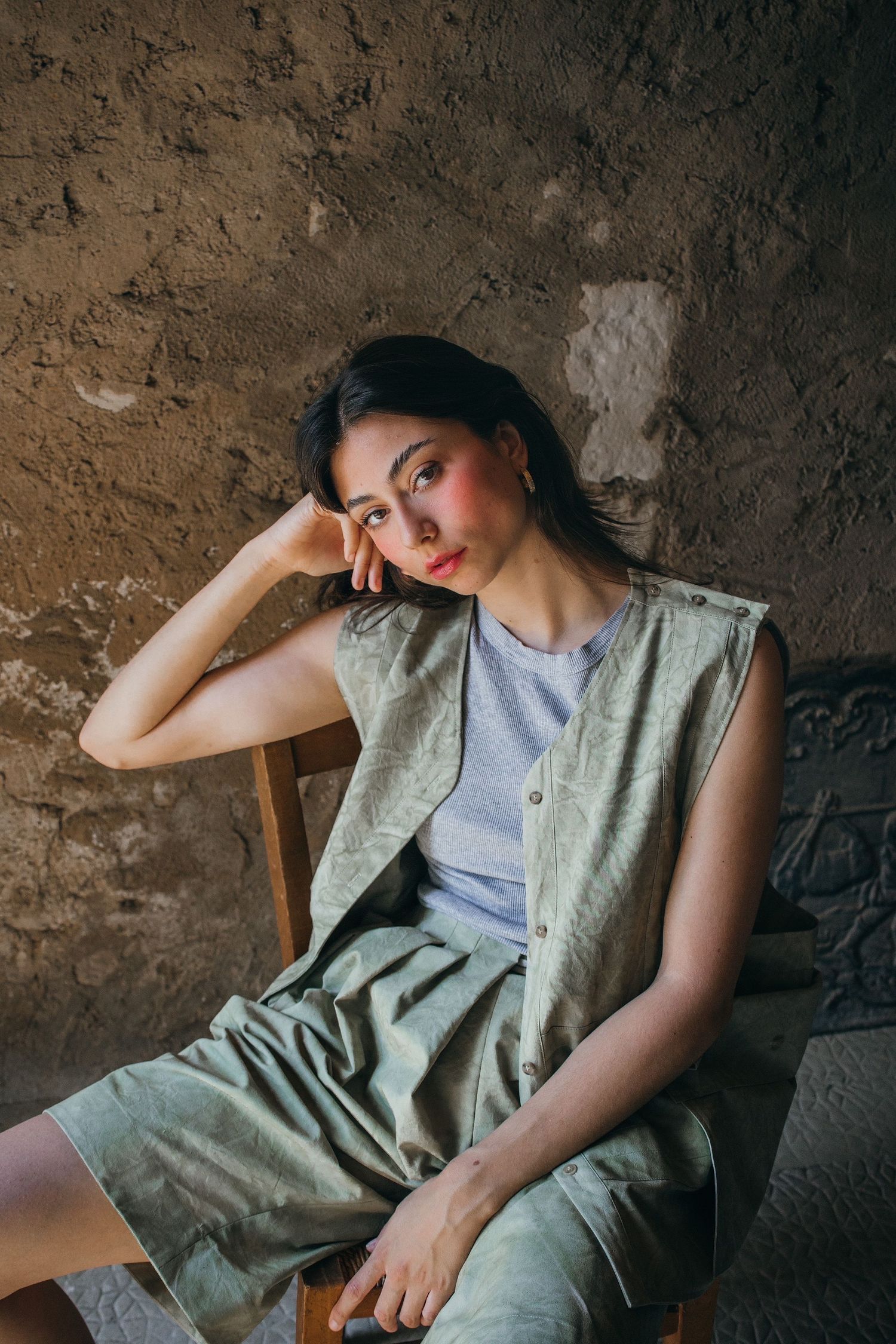Casual portrait in olive clothing against a textured brown wall.