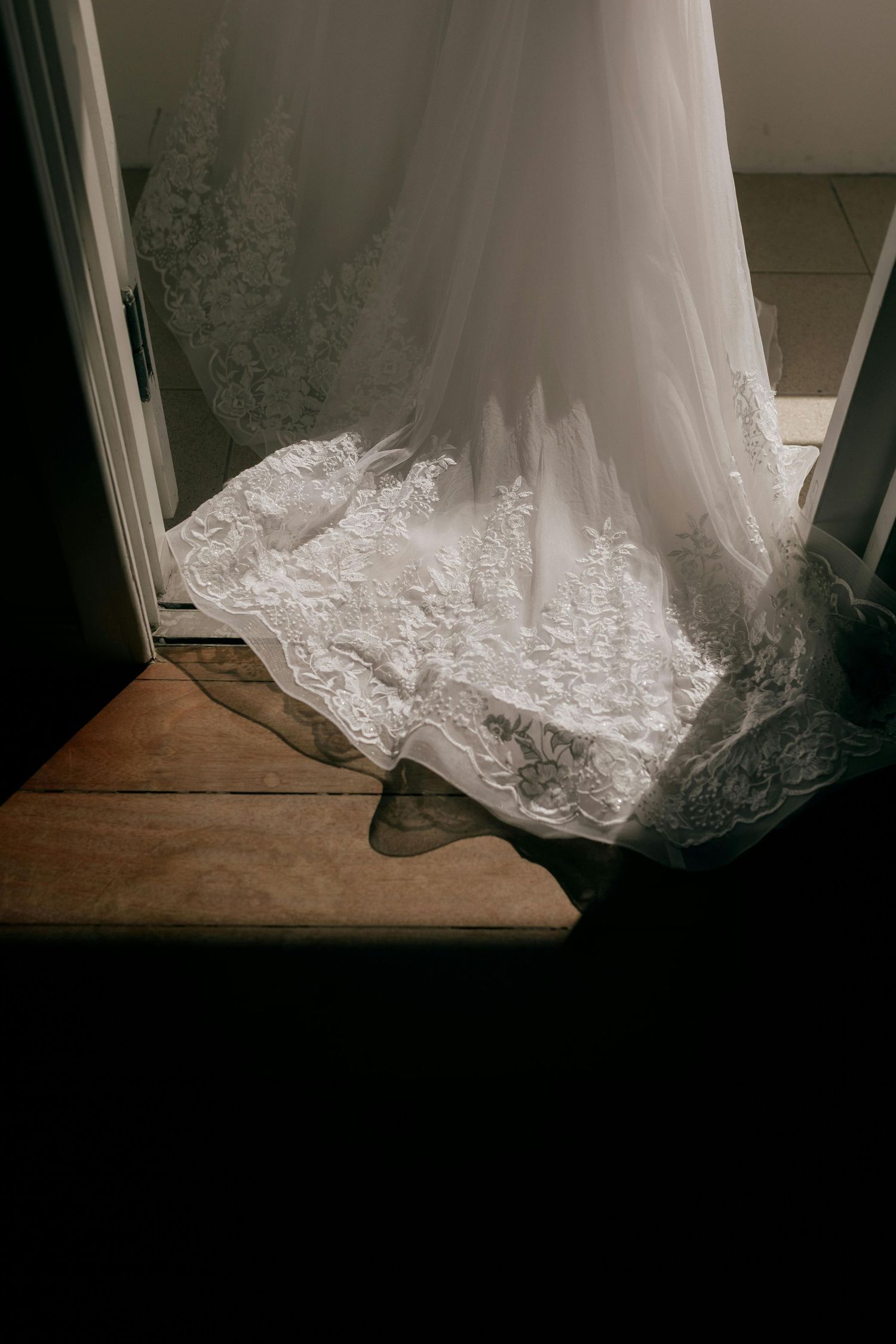 Ourlet en dentelle d’une robe de mariée blanche sur parquet foncé
