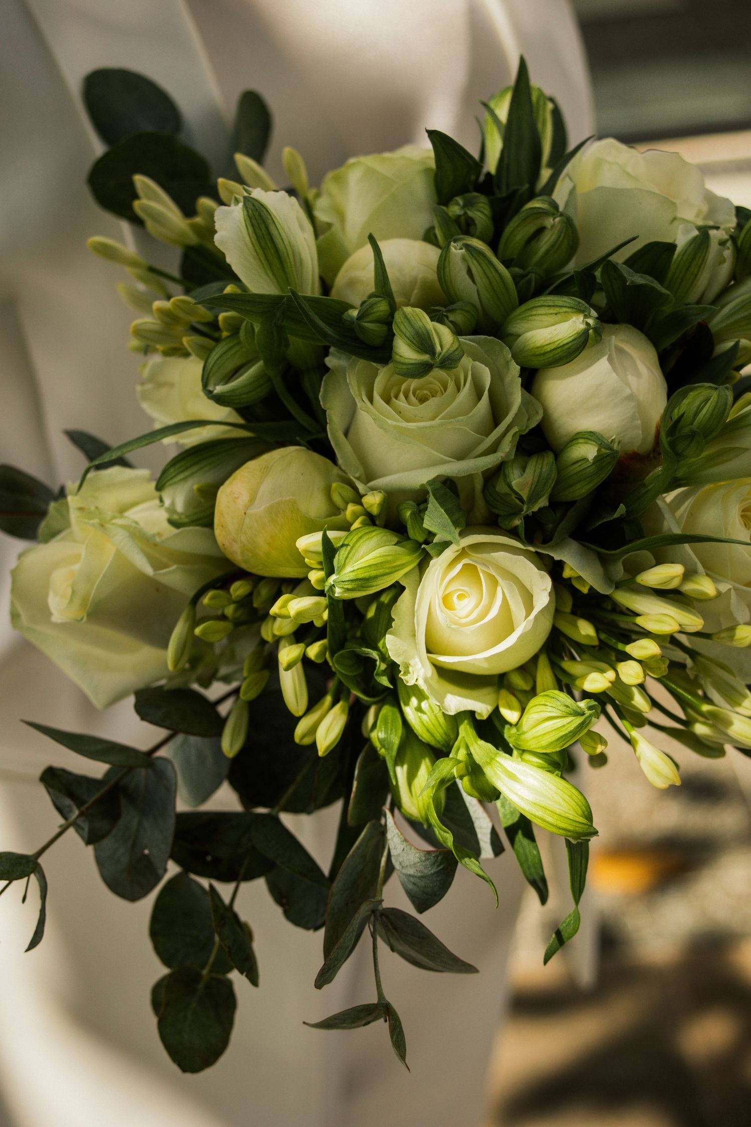 Bouquet de mariée avec roses crème et feuillage vert à la lumière naturelle