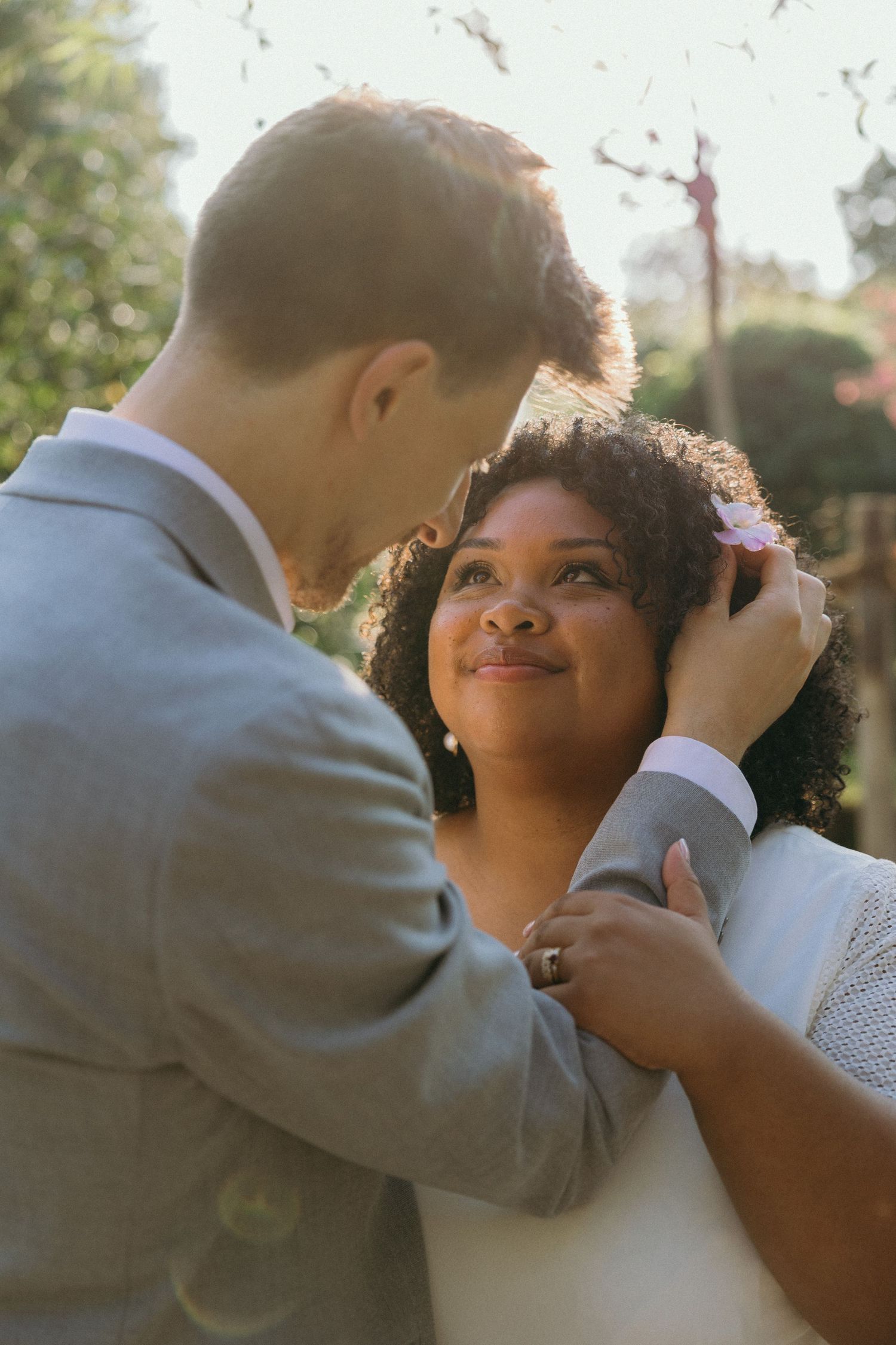 A couple shares intimate moments during their sunset wedding photoshoot in a garden setting.