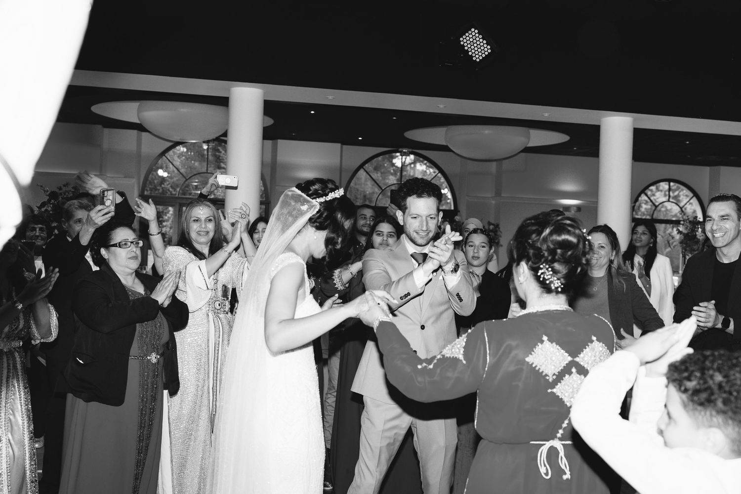 Invités de mariage en noir et blanc dansant et célébrant avec les bras levés, cantenay-épinard
