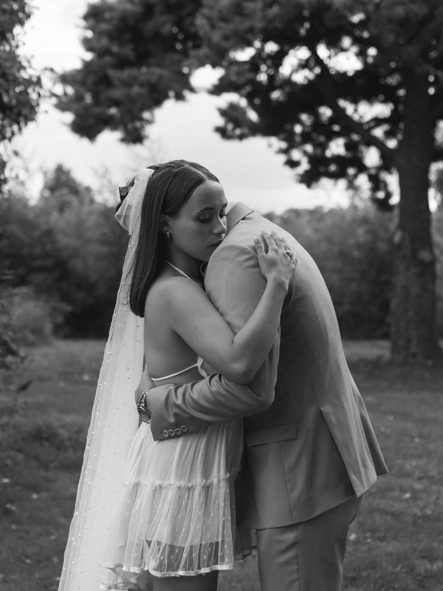 Photo intime en noir et blanc d’un couple de mariés s’enlaçant devant des feuilles de palmier à Angers